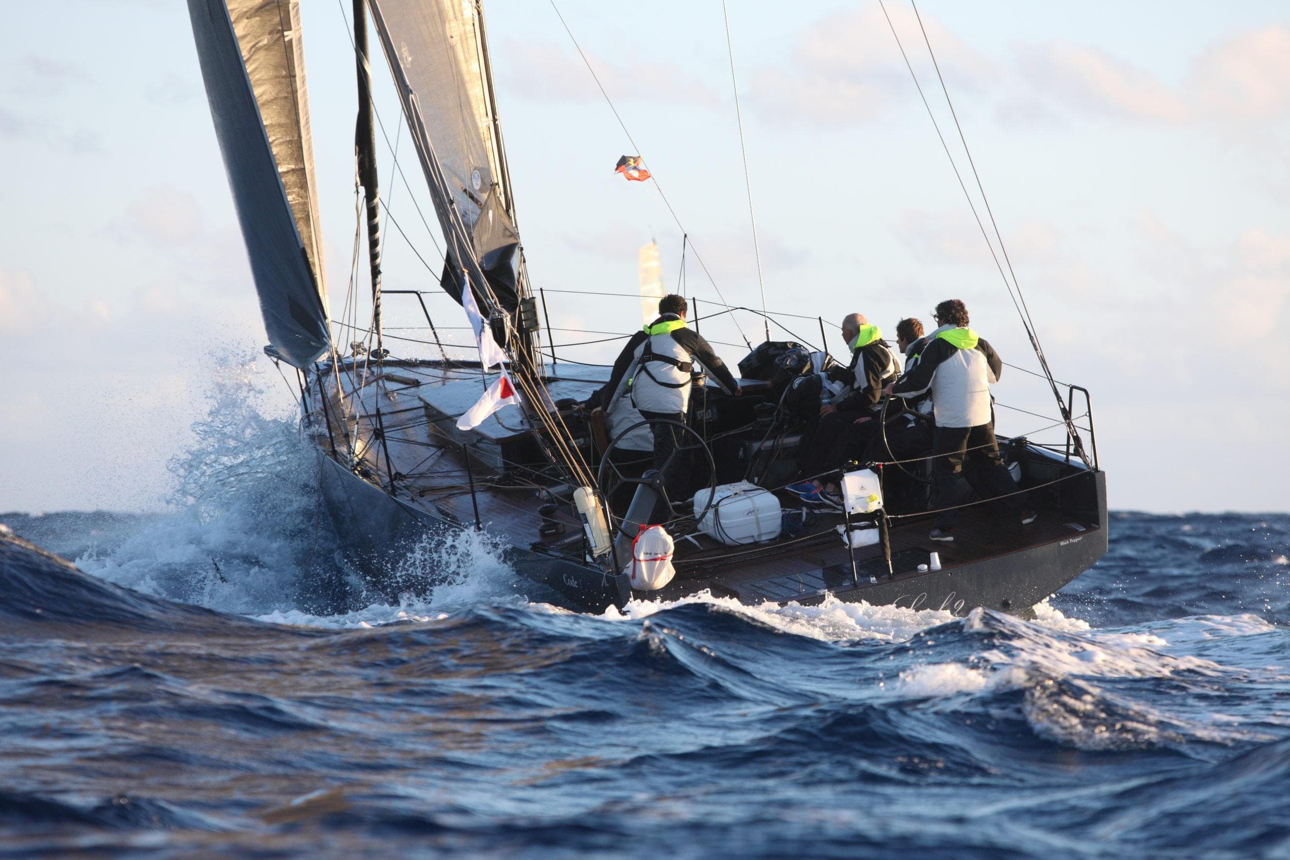 Sailboat navigating rough seas, crew onboard, Black Pepper CODE 1, 2025 model.