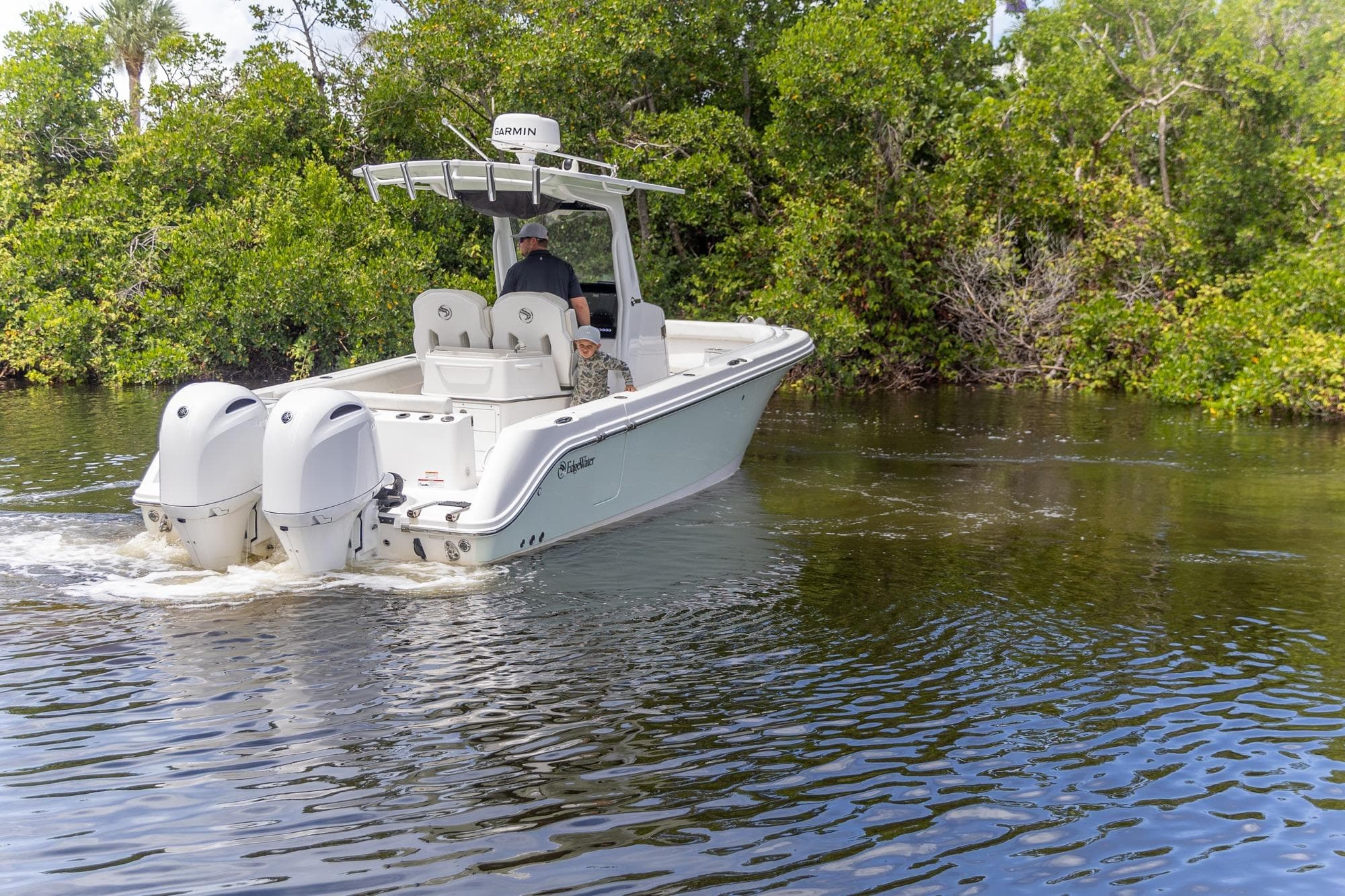 2023 Edgewater 262CC boat cruising on a calm river surrounded by lush greenery.