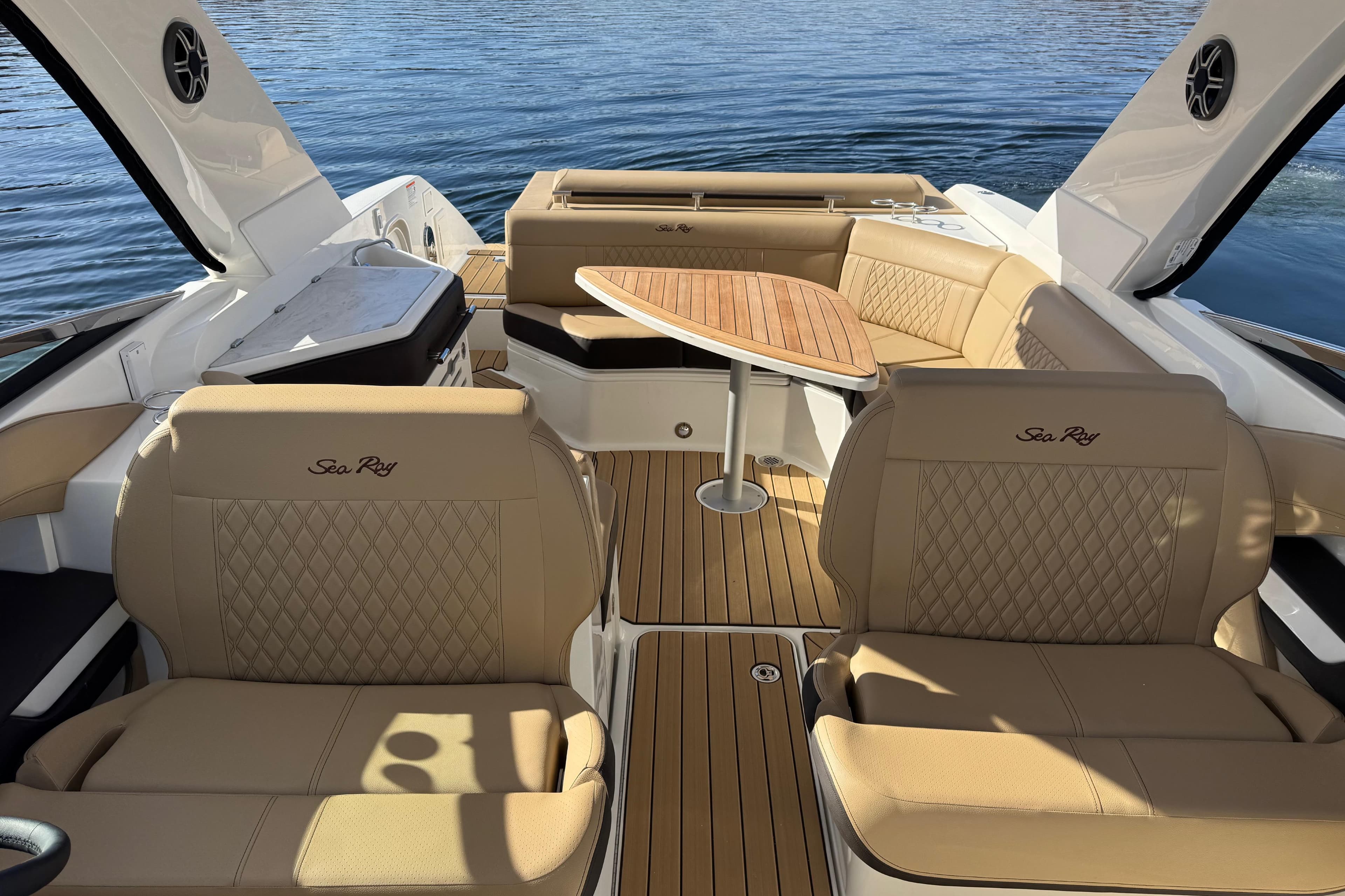 2026 Sea Ray SLX 310 boat interior with tan leather seating and wooden table on water.