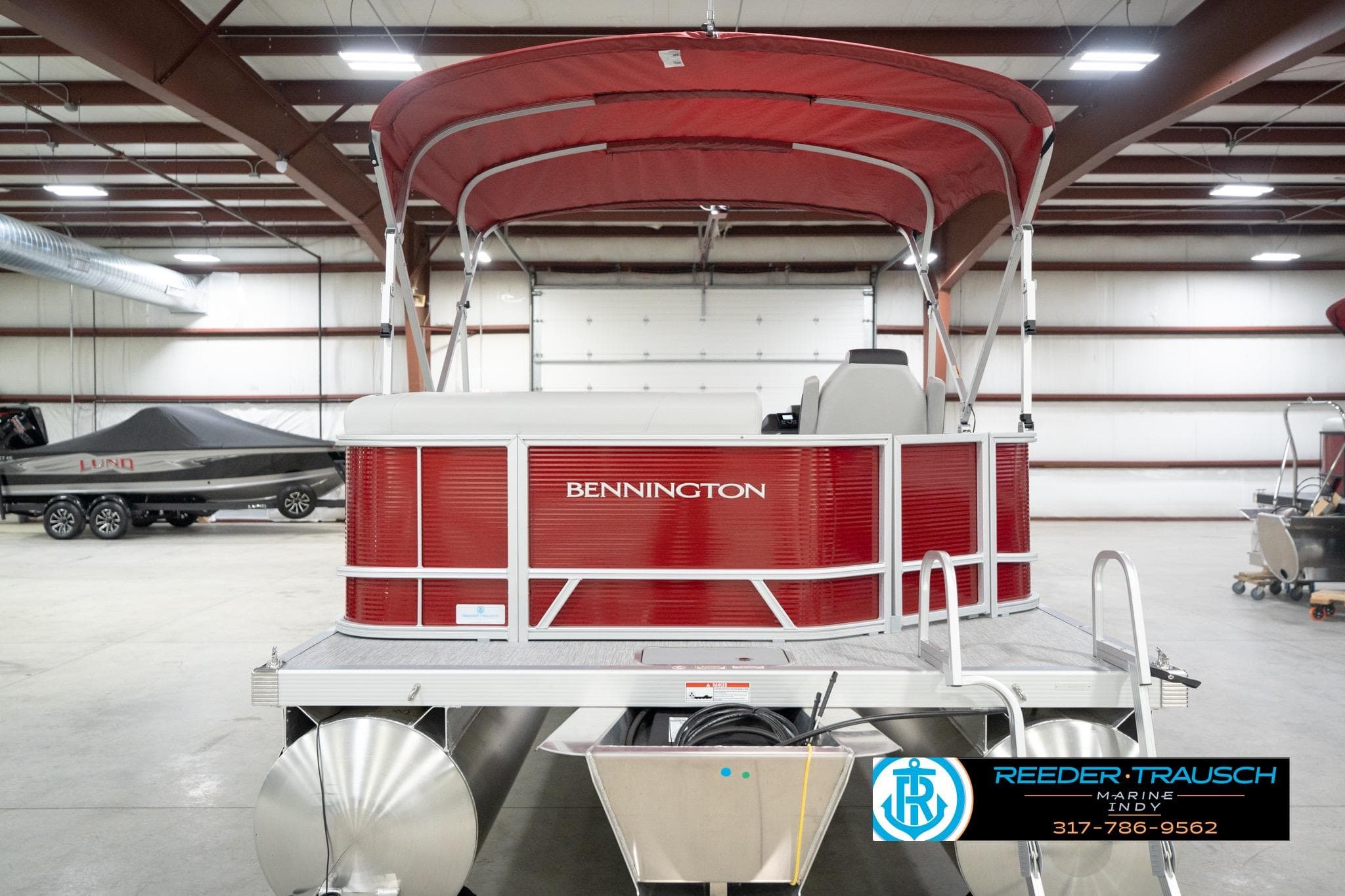 2026 Bennington 20 SL pontoon boat with red canopy in a showroom.