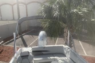 2023 Hurricane SunDeck Sport 188 OB boat near palm tree in parking lot.