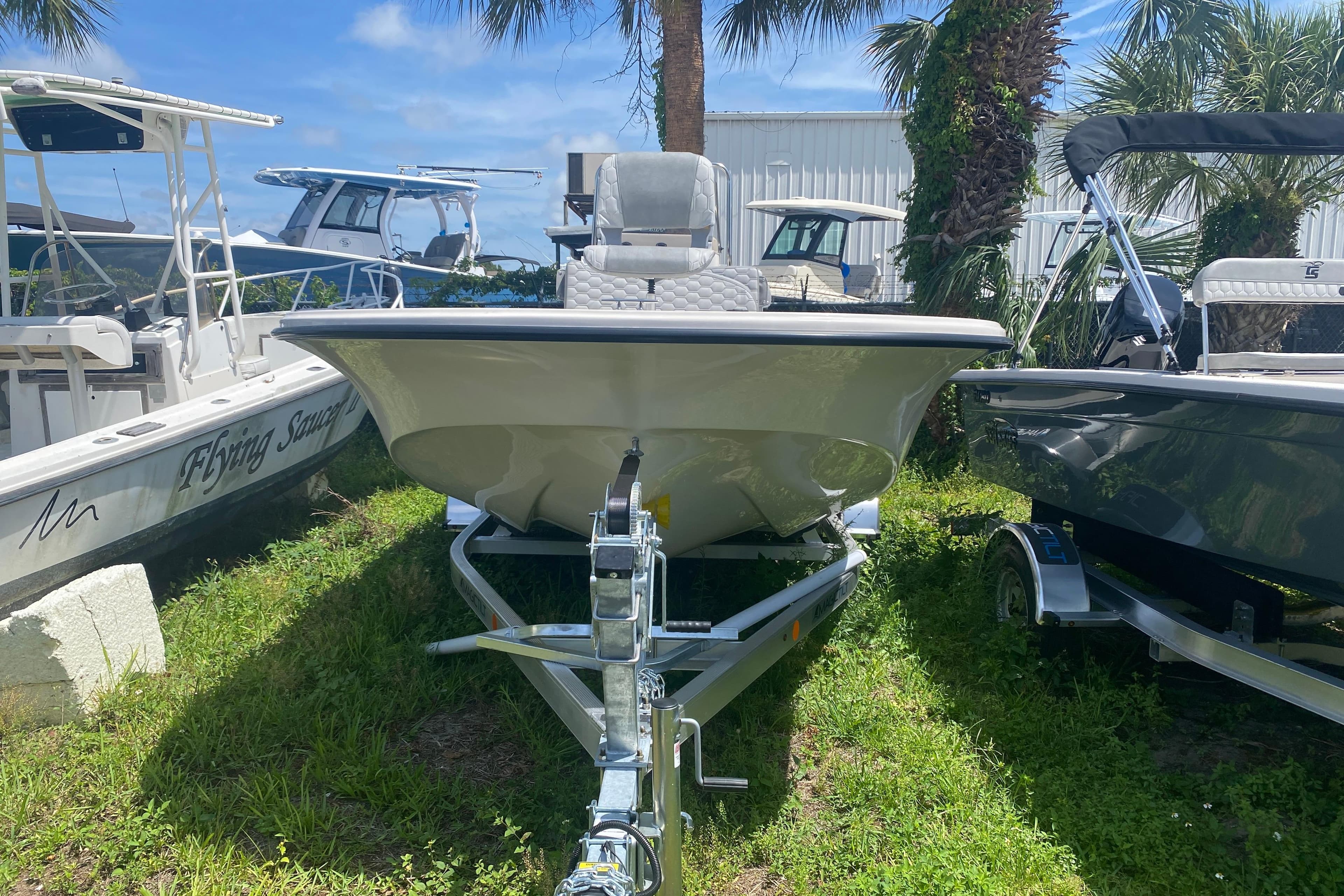 2026 Carolina Skiff 19 LS boat on trailer, surrounded by palm trees and other boats.