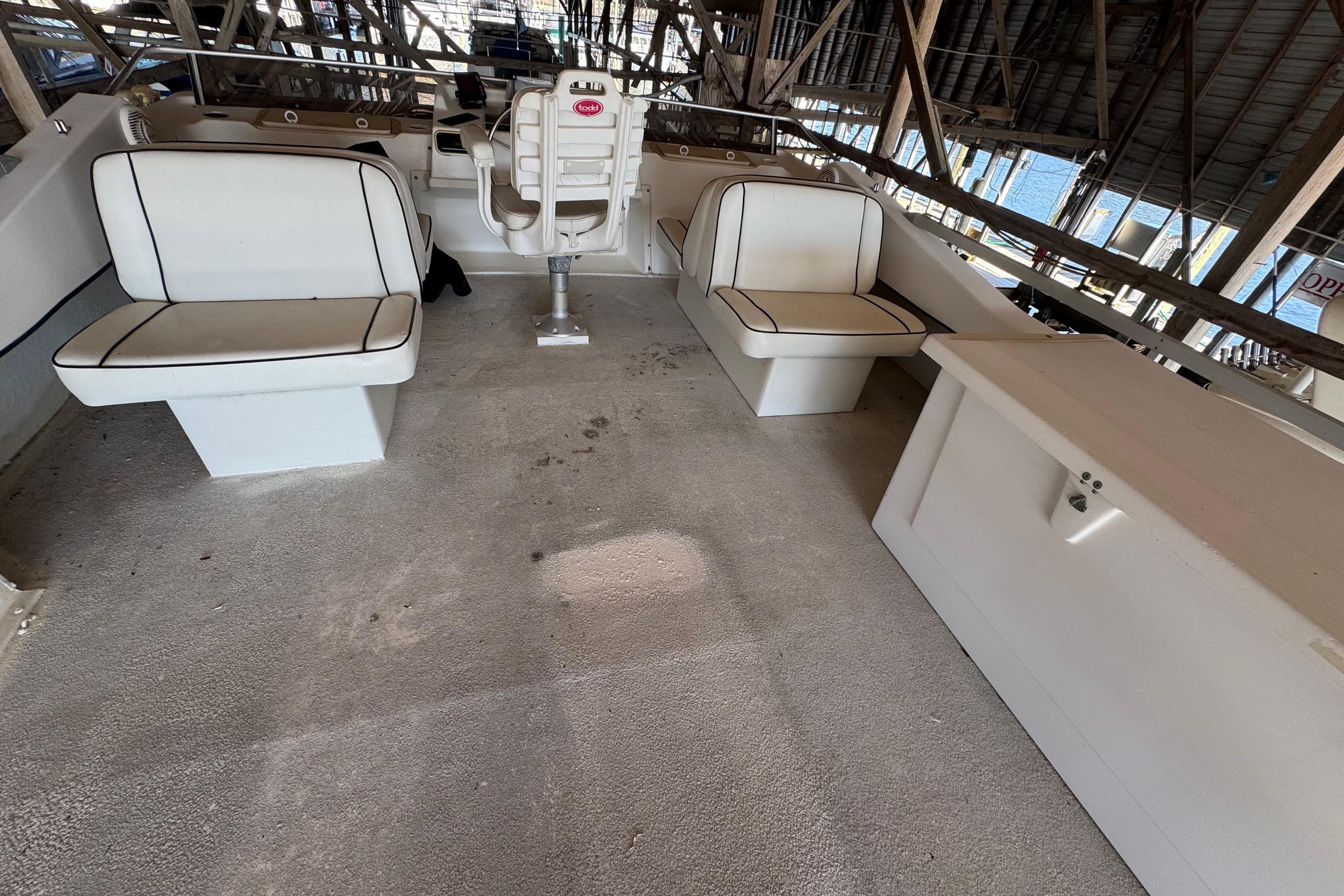 1999 Gibson Houseboat 50 interior with white seating and helm in a covered dock.