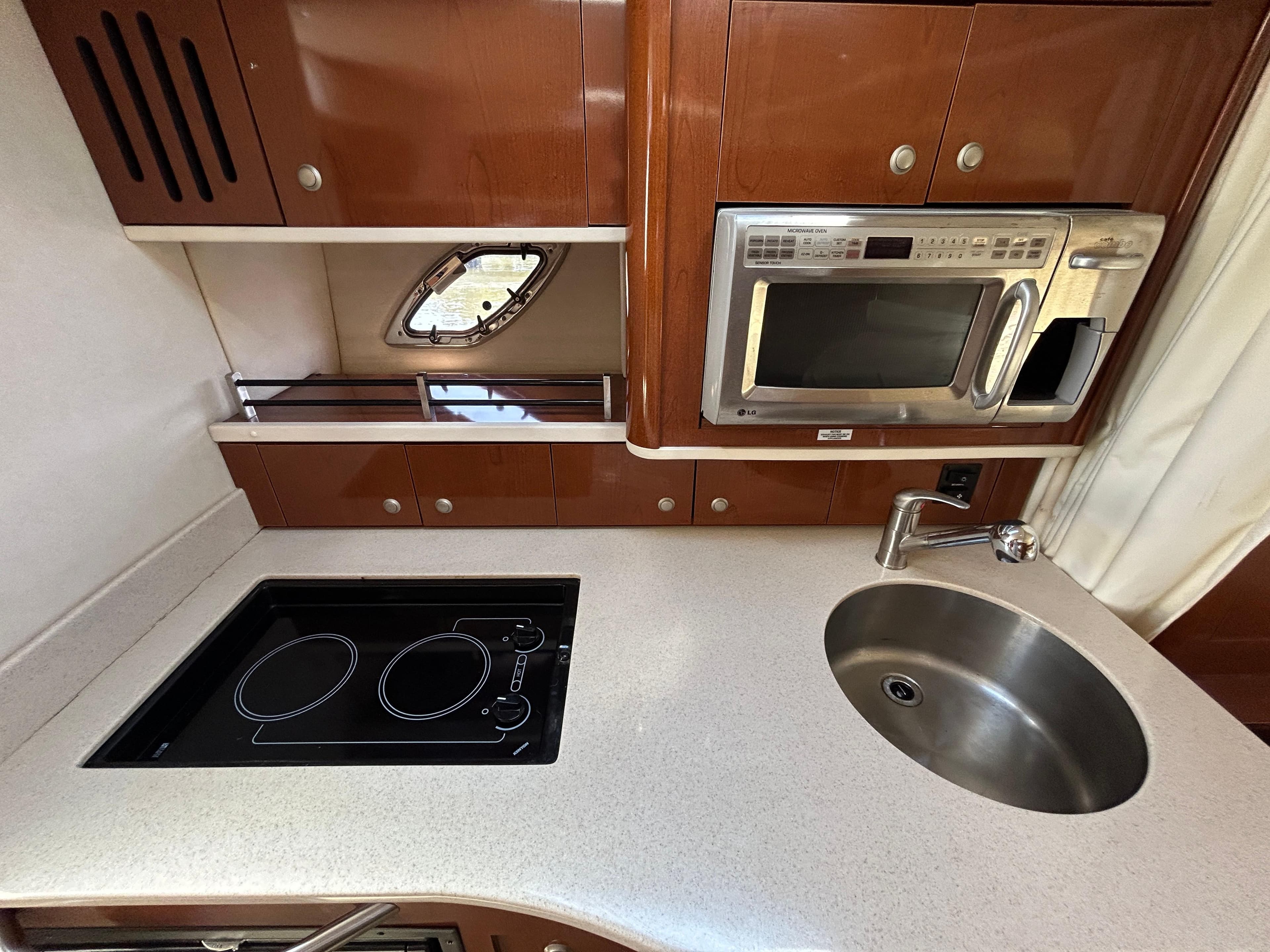 2008 Sea Ray 330 Sundancer kitchen with stove, microwave, and sink.