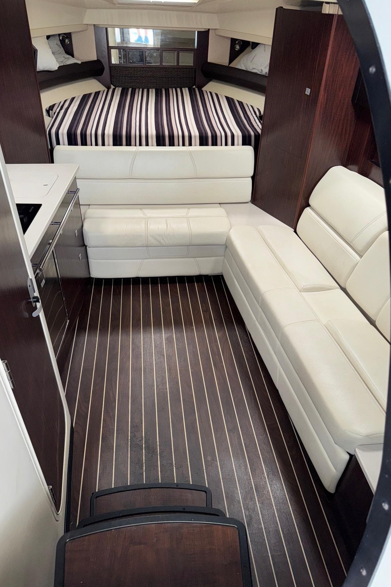 Interior of 2013 Monterey 320 Sport Yacht with modern seating and striped bedding.