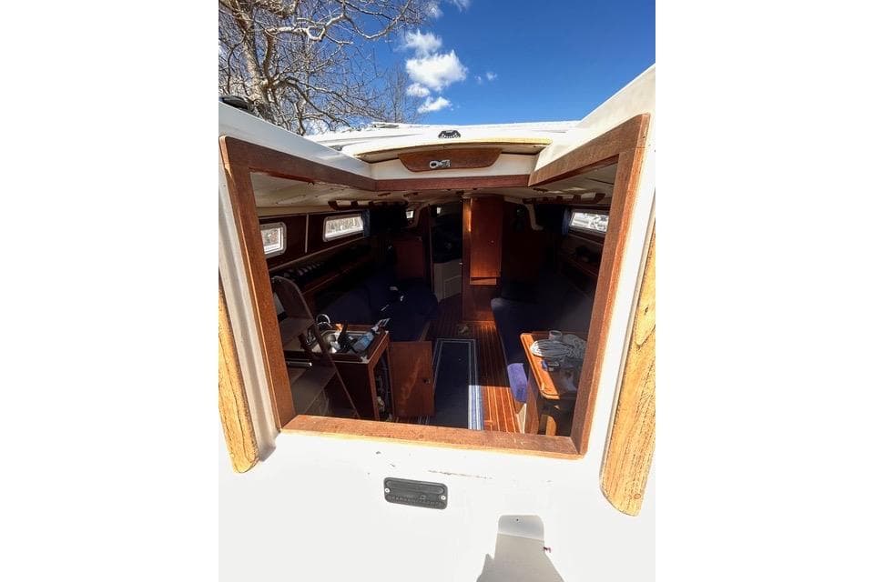 Interior view of 1984 Pearson 34 sailboat cabin with wooden accents and blue sky above.