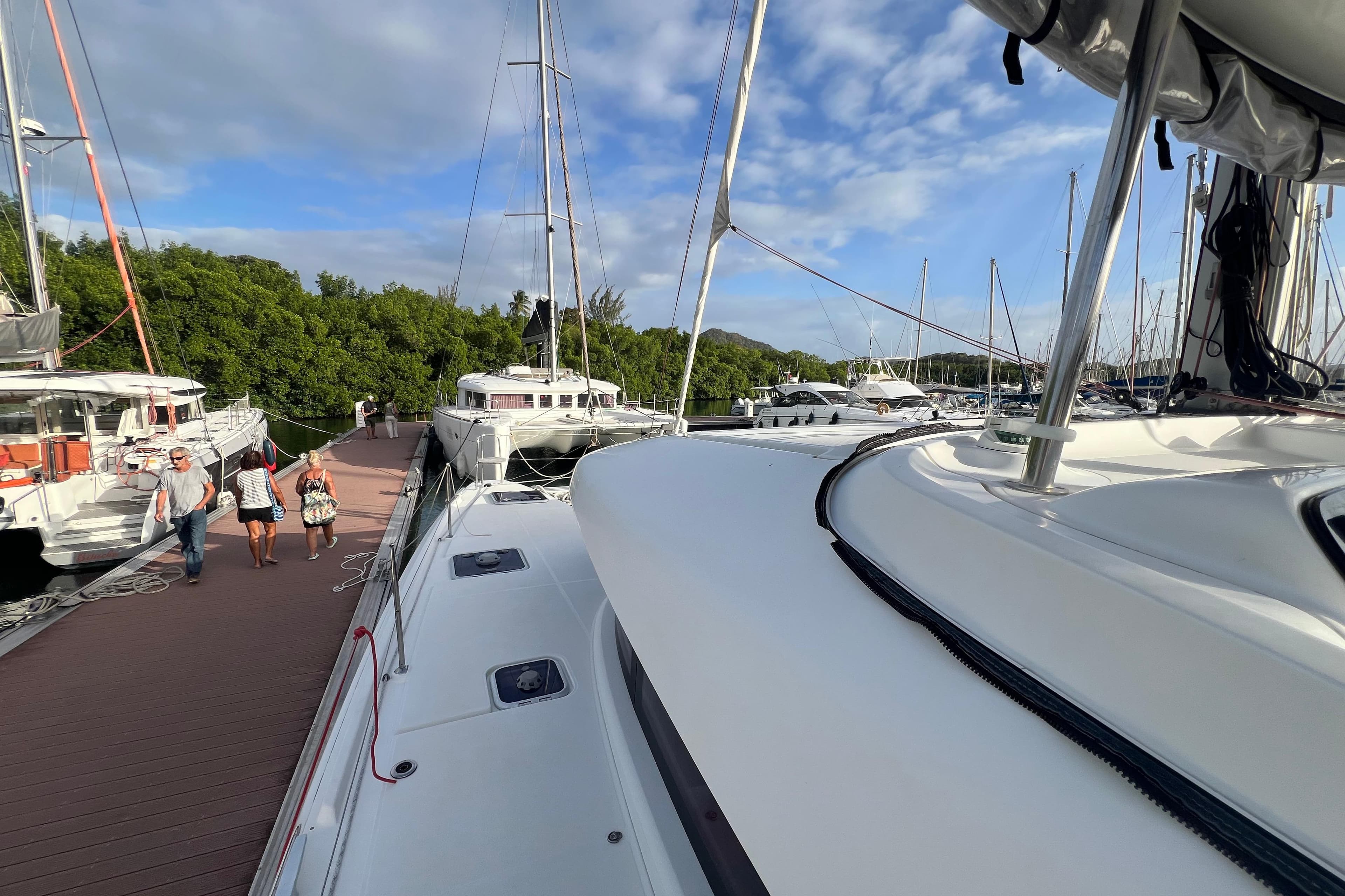 2018 Lagoon 42 catamaran docked at marina with people walking on pier.