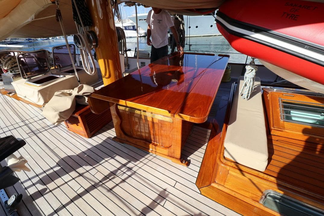 Classic 1933 Camper & Nicholsons wooden ketch deck with polished table and seating area.