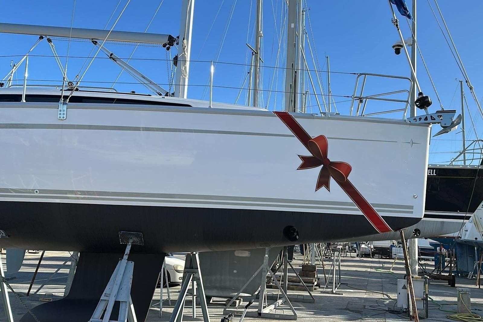 2023 Bavaria 34 Cruiser yacht with decorative red ribbon, docked under clear blue sky.