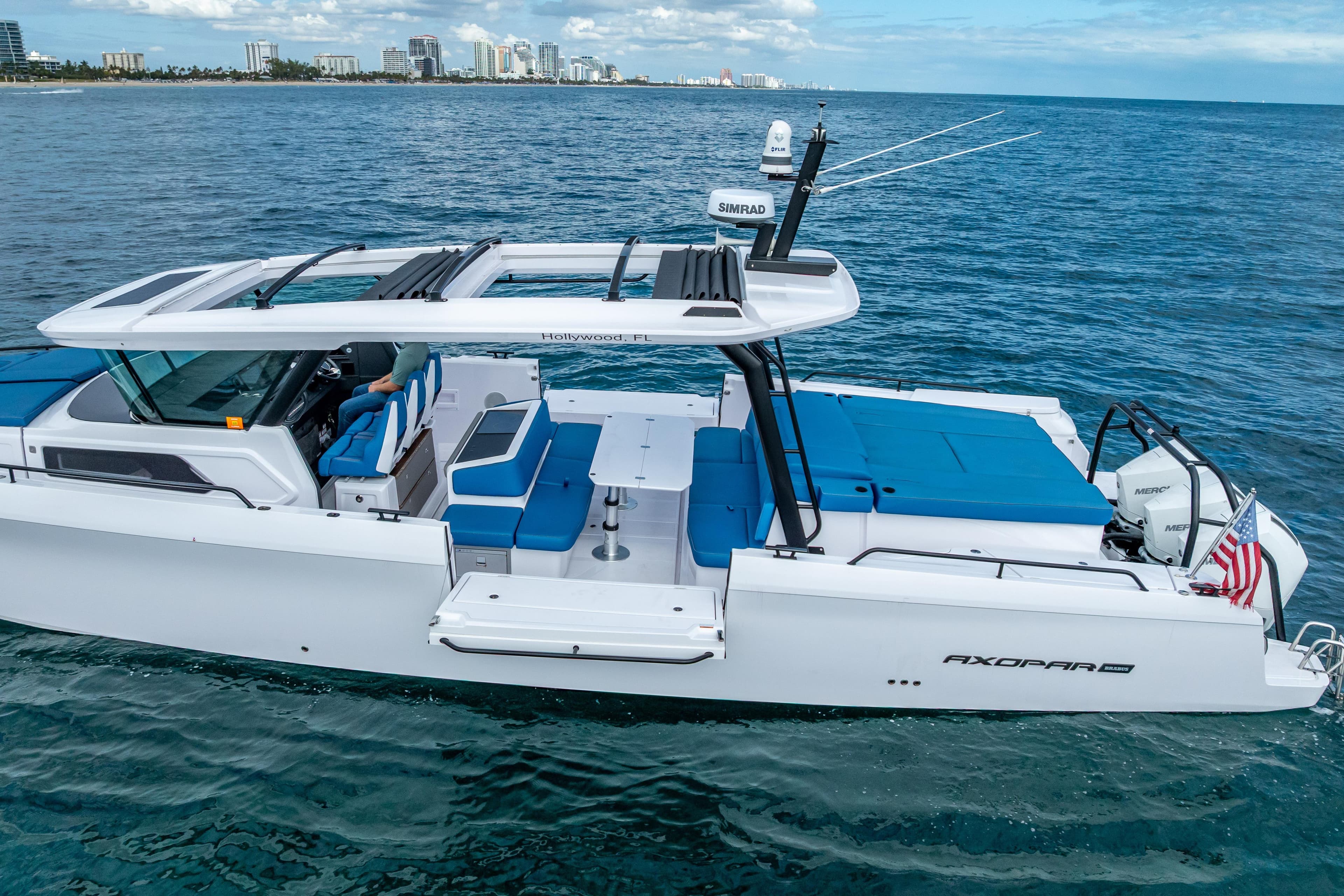 2025 Axopar 45 Cross Top boat cruising on open water near city skyline.