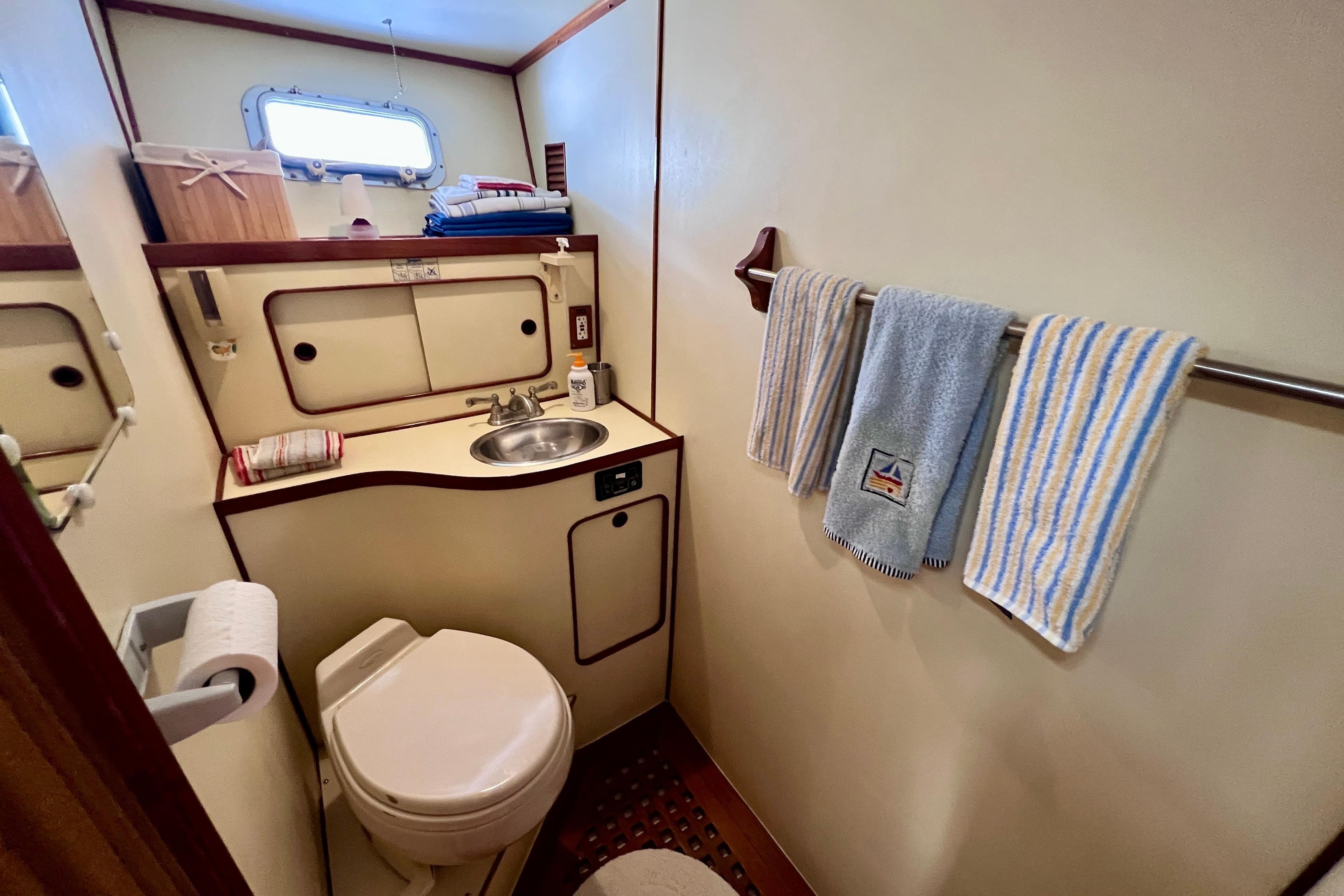 1984 Kha Shing Spoiler yacht bathroom with sink, toilet, and striped towels.