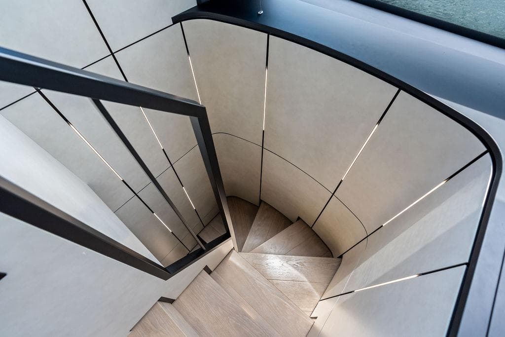 Modern spiral staircase inside 2025 Pershing GTX 80 yacht, featuring sleek design and lighting.