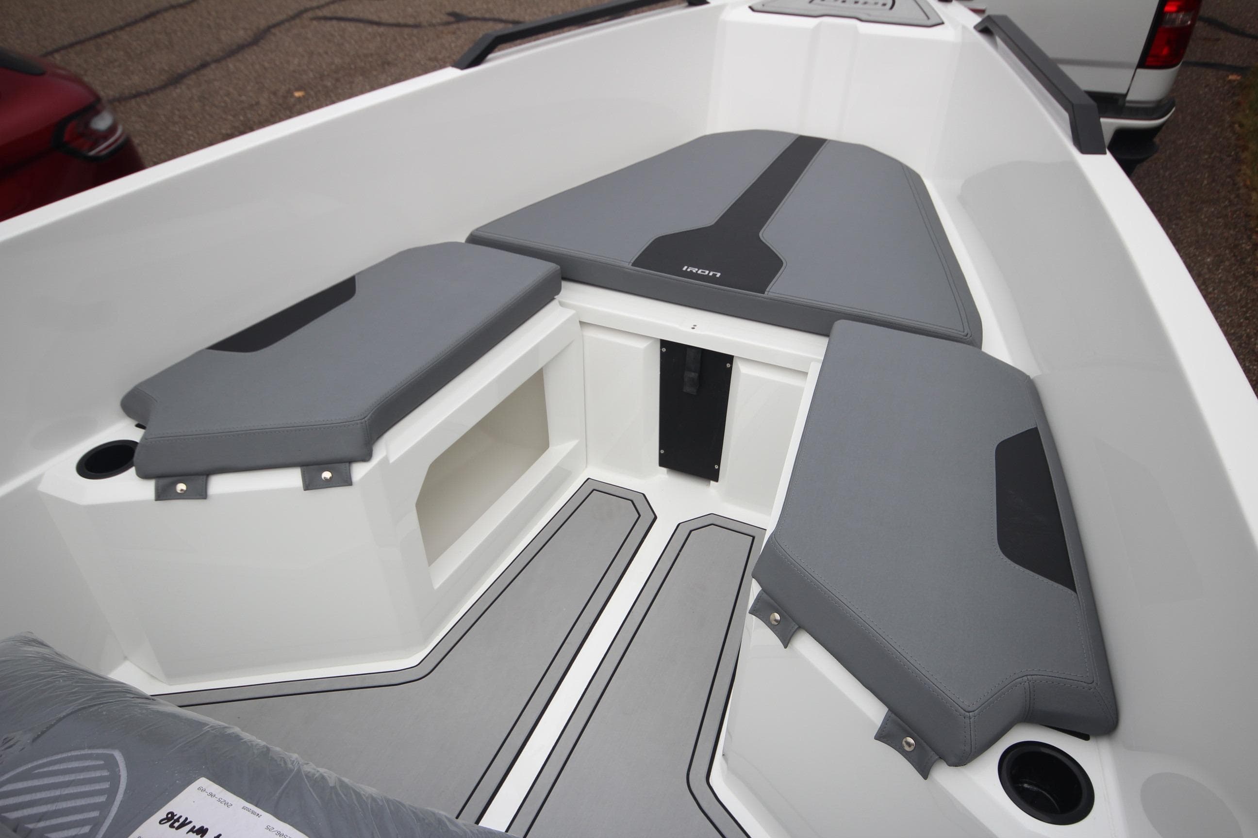 2026 Iron 767 T-top boat interior with gray cushioned seating and storage compartments.