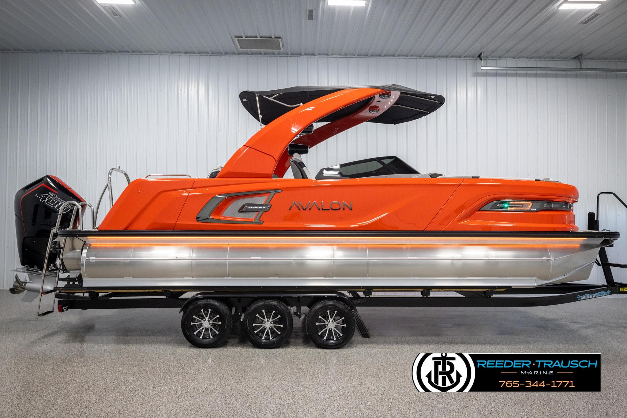 2024 Avalon Excalibur VRB pontoon boat in vibrant orange, displayed indoors on a trailer.