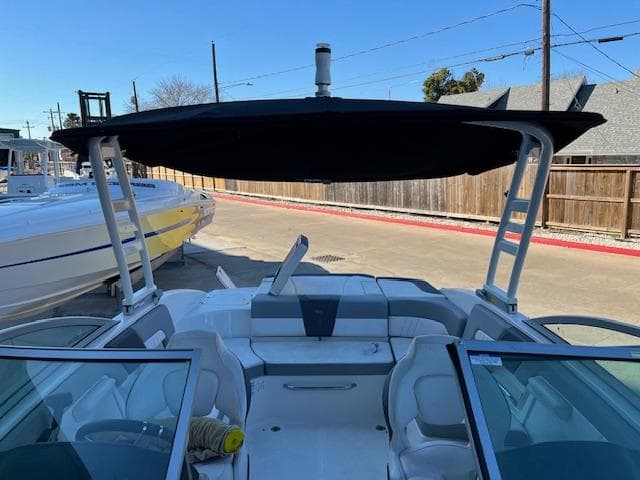 2020 Chaparral 23 SSi boat with black canopy and white seating, docked outdoors.