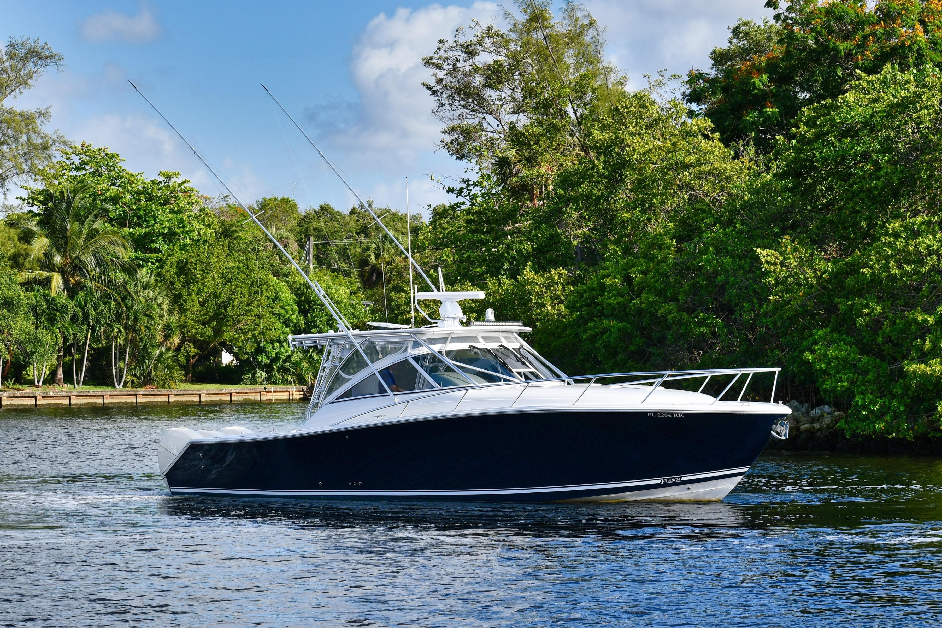 2009 Jupiter 39 Express boat cruising on a scenic waterway surrounded by lush greenery.
