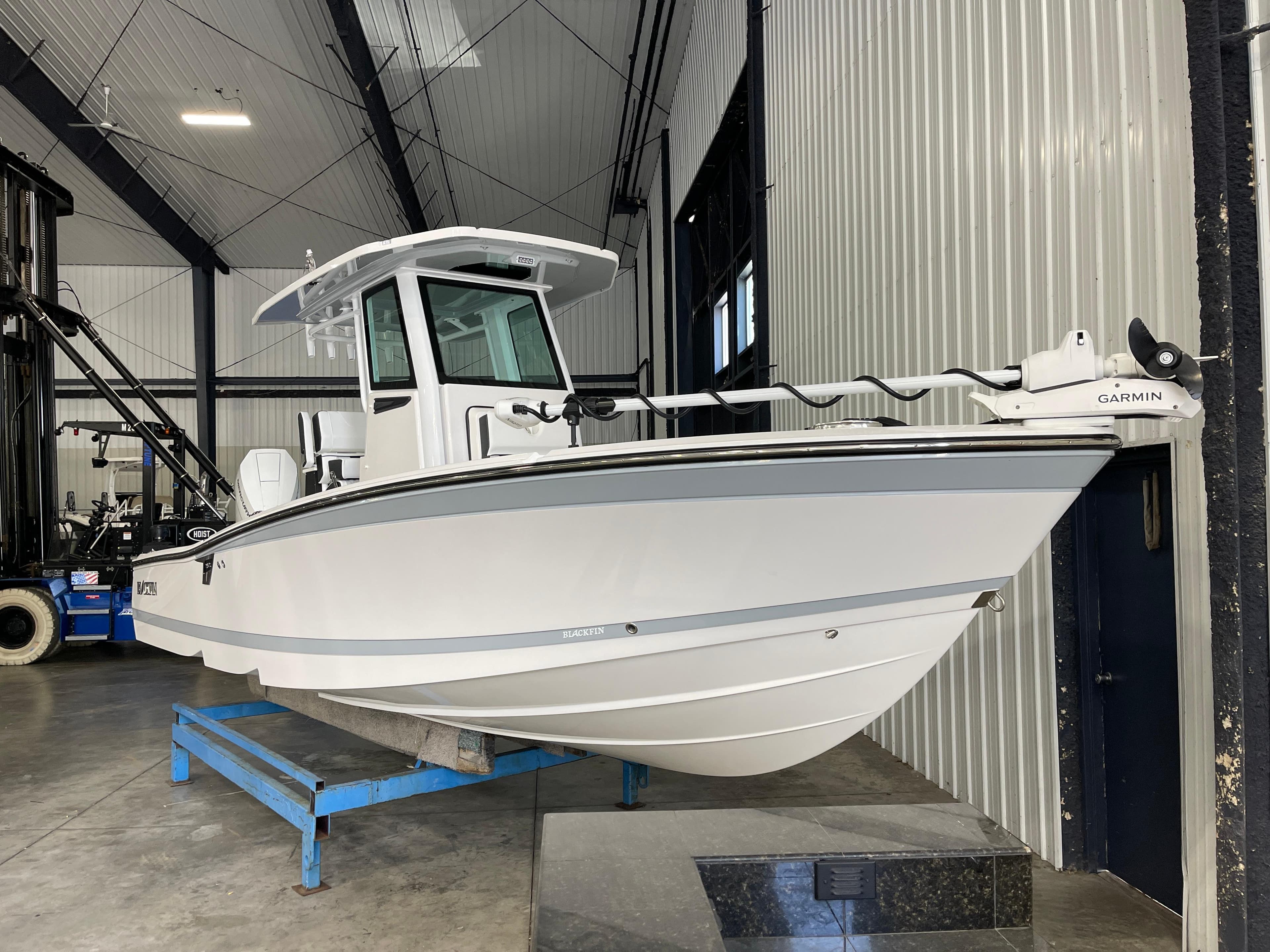2026 Blackfin 262 HB boat in a warehouse, mounted on a blue stand.