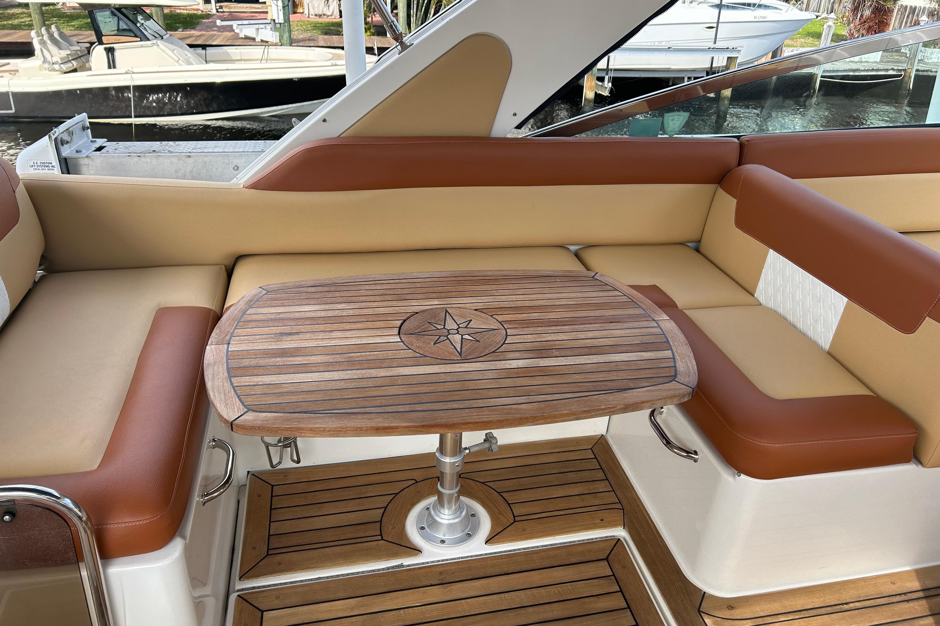 Luxurious seating area on a 2014 Sea Ray 370 Venture with wooden table and leather cushions.