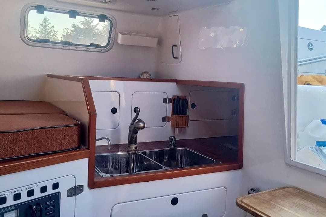 Compact kitchen area in a 2012 Hughes 40 boat, featuring a sink and storage cabinets.