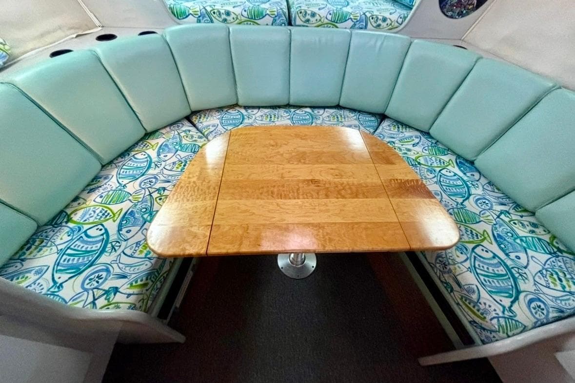 1992 Tiara Sport 270 Sport interior with teal seating and fish-patterned cushions around a wooden table.