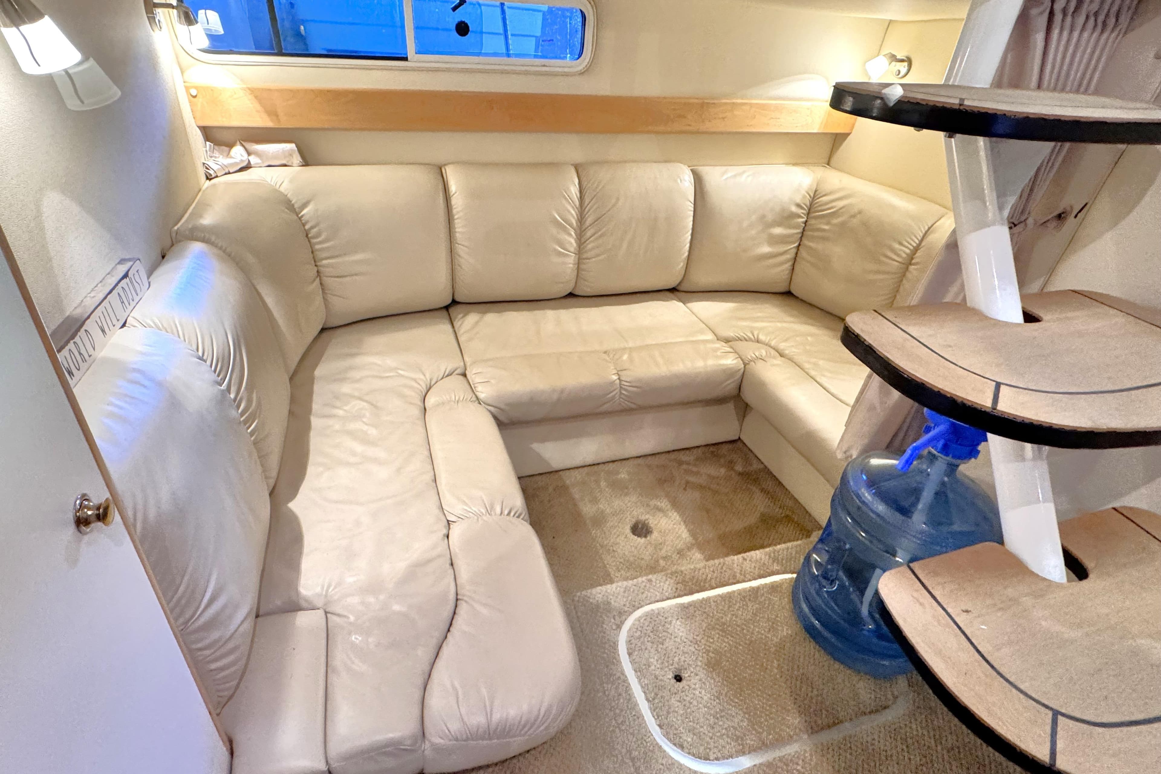 Interior of 2002 Larson Cabrio 310 boat with beige leather seating and carpeted floor.