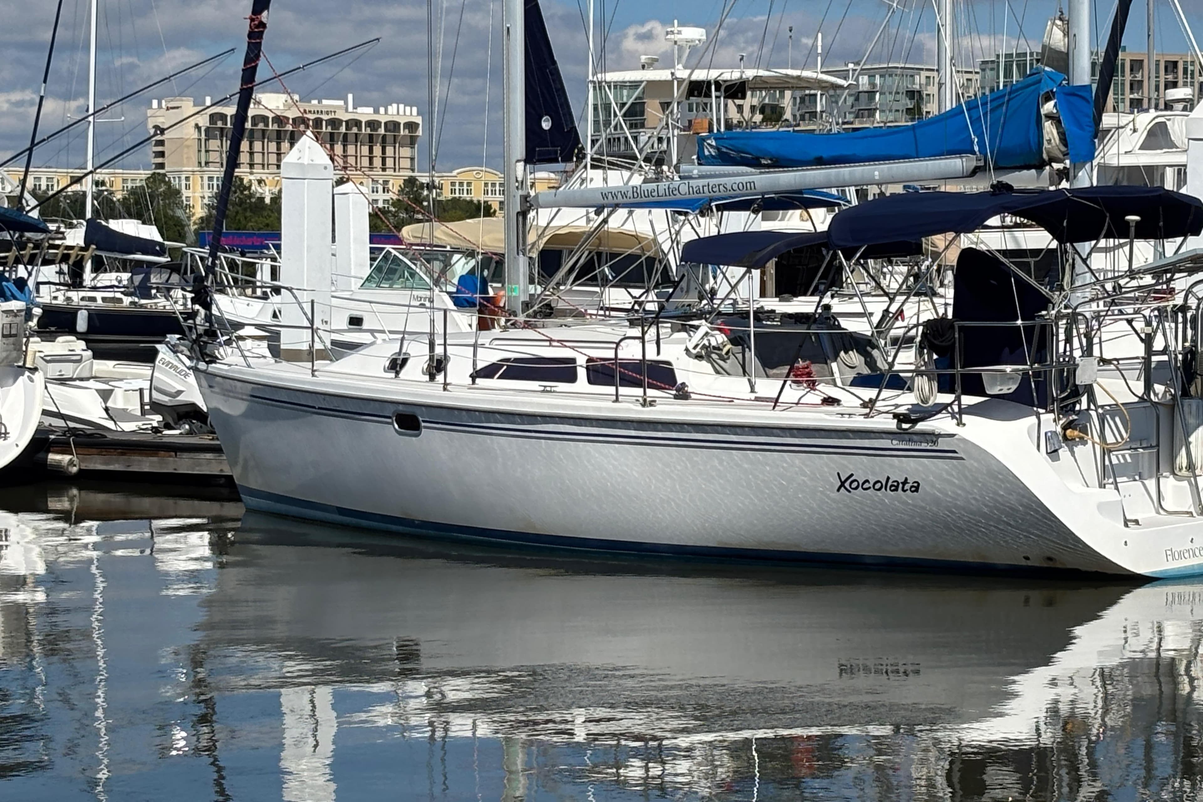 2006 Catalina 320 sailboat docked in a marina, reflecting on calm water.