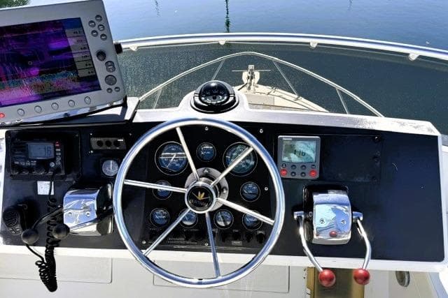 Cockpit view of a 1991 Bertram 28 boat with steering wheel and navigation equipment.