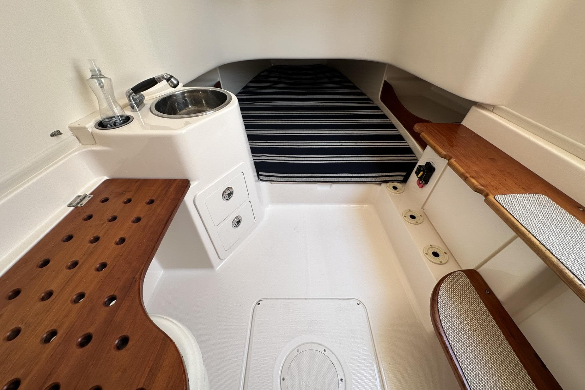 2014 Grady-White Canyon 336 cabin interior with sink, striped bedding, and wooden accents.