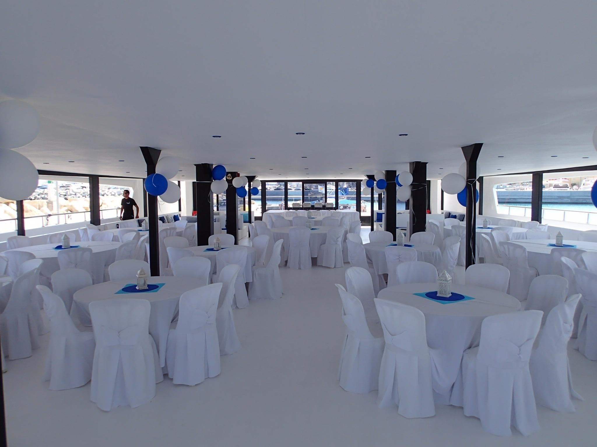 2015 Power Catamaran interior setup for event with white tablecloths and blue decorations.