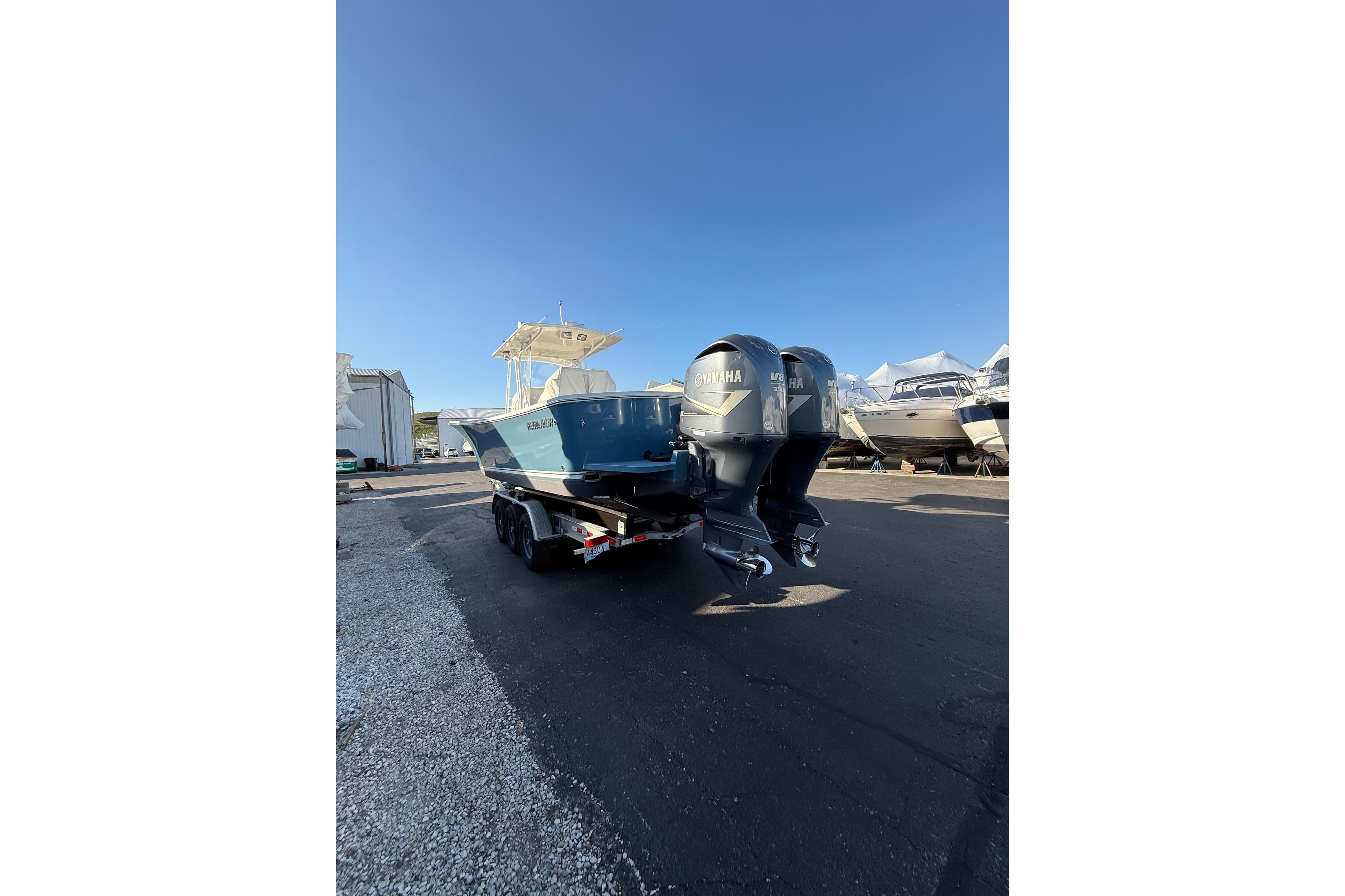 2010 Regulator 34SS boat with dual Yamaha engines on a trailer, parked outdoors.