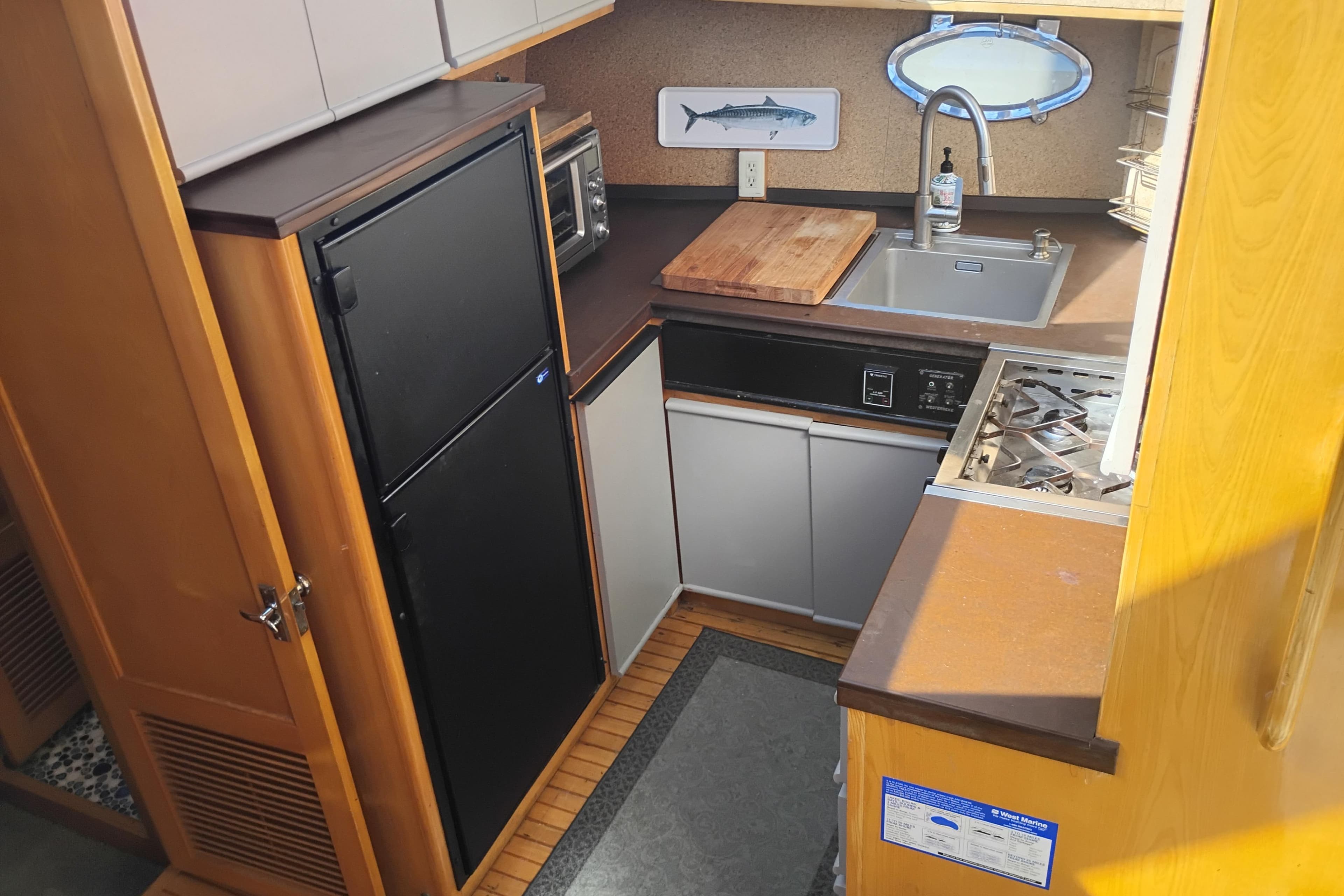 Compact kitchen in 1988 PT 52 AFT Cabin Motor Yacht with sink, stove, and fridge.