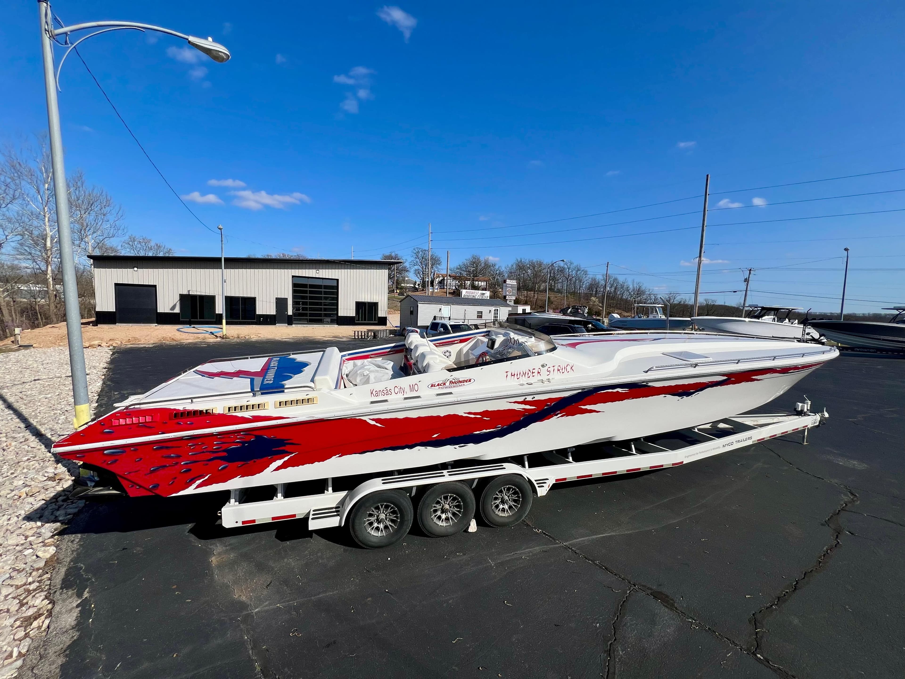 1999 Black Thunder 430 Flat Deck boat on trailer, vibrant red and white design.