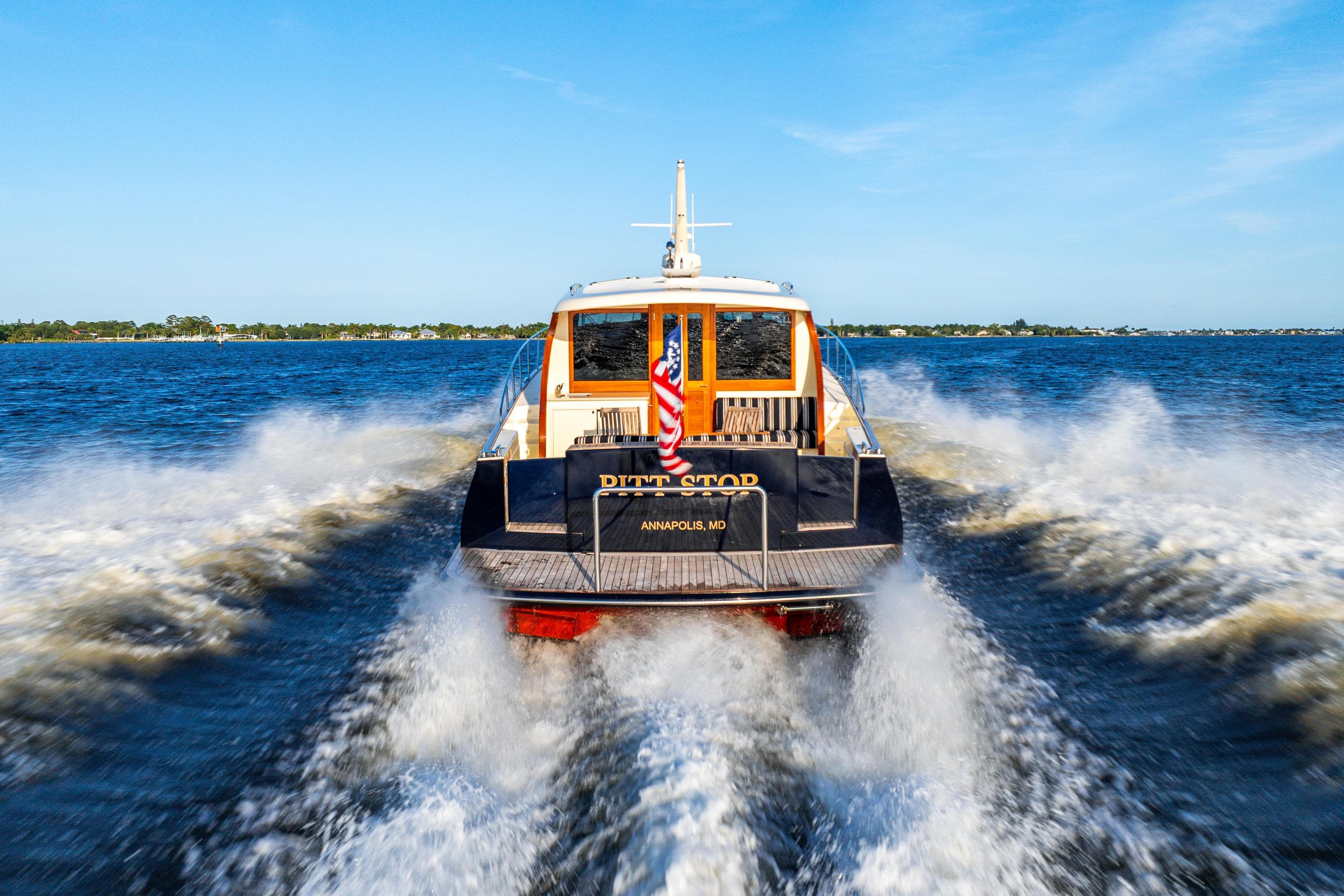 2020 Palm Beach Motor Yachts PB55 cruising on open water, rear view.