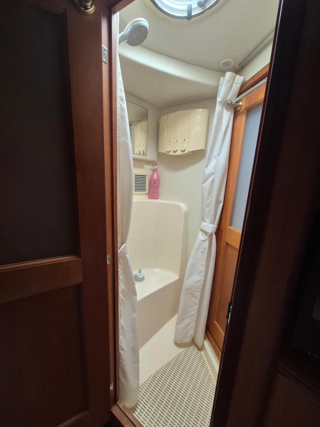 Shower area in 2002 Silverton 38 Convertible boat with curtain and wooden door.