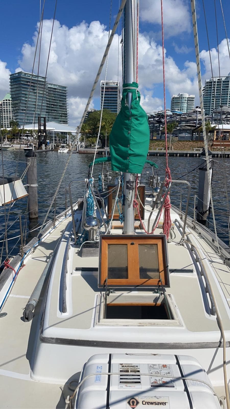 1986 Cabo Rico CB38 sailboat docked in marina, city skyline in background, clear sky.