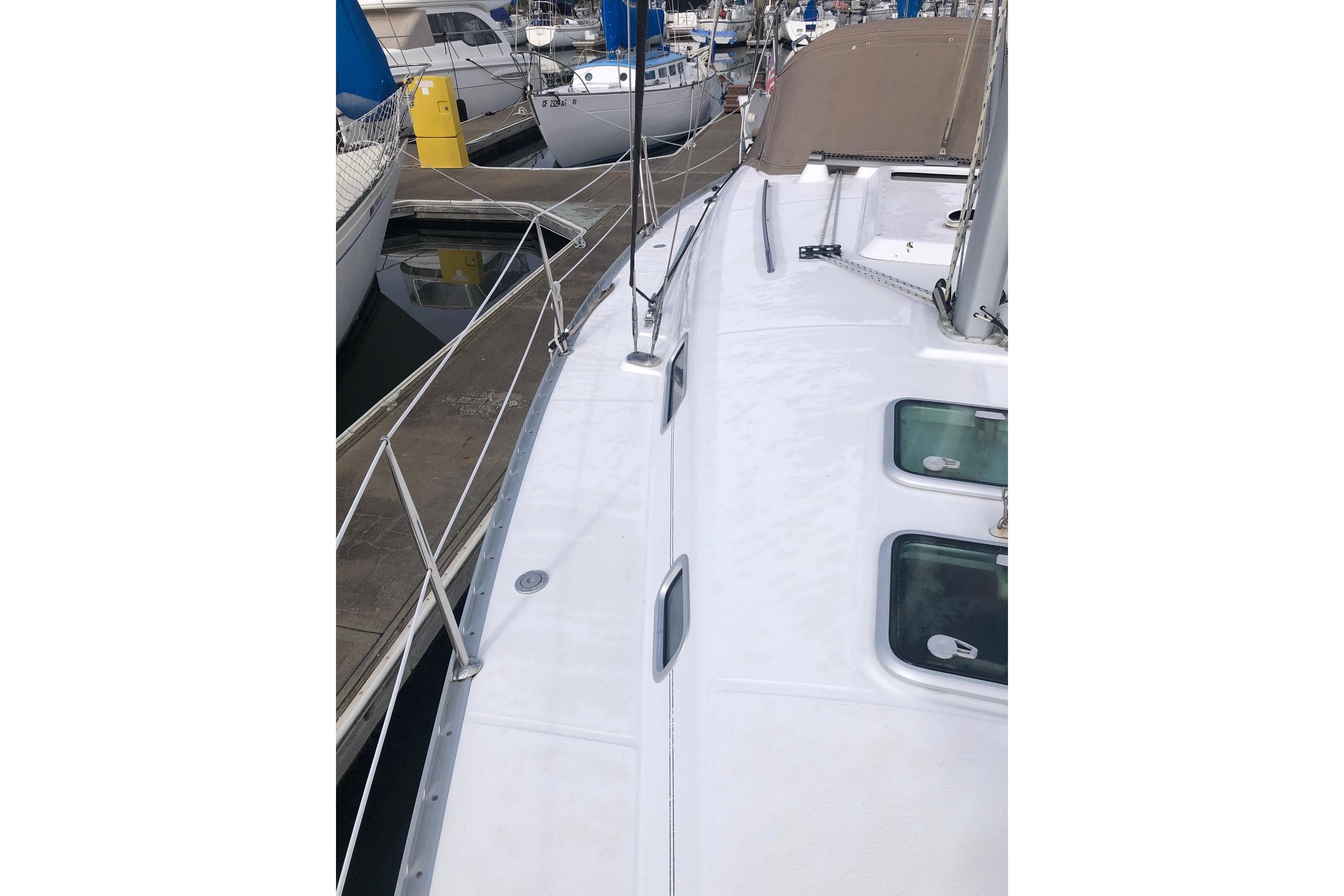 2003 Beneteau 361 sailboat deck view at marina, showcasing sleek design and moored vessels.