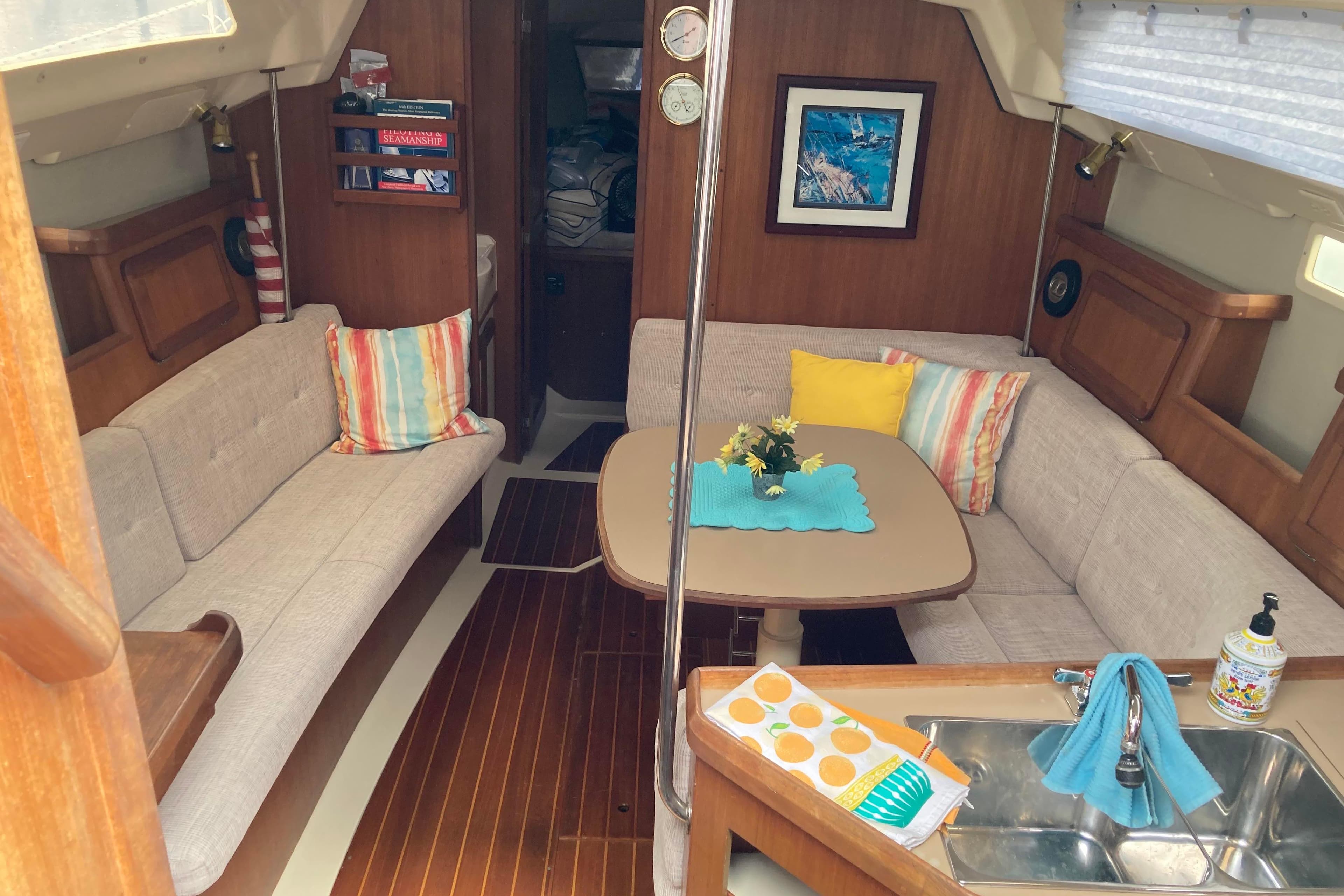 Cozy interior of a 1993 Hunter 33.5 sailboat with seating, table, and colorful cushions.