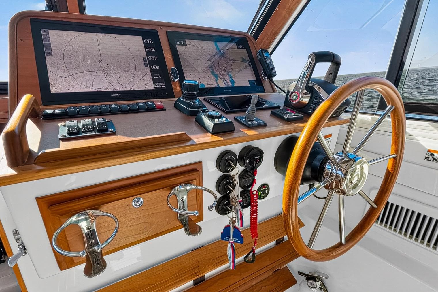 2024 Back Cove 39O helm with dual navigation screens and wooden steering wheel.