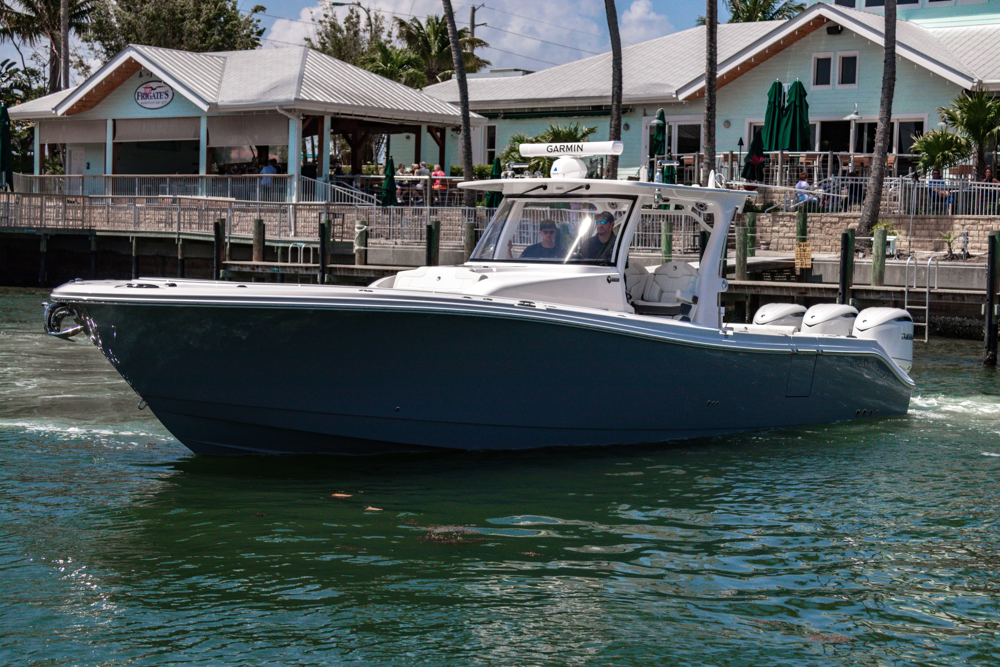 2025 Edgewater 370CC boat cruising near waterfront buildings.