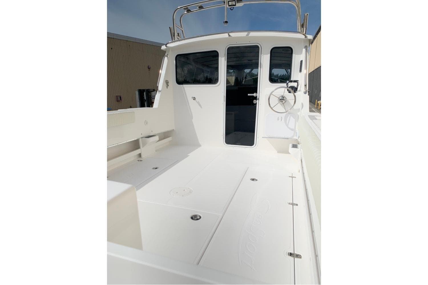 2026 Sea Sport Kenai 2600 boat deck with steering wheel and cabin entrance.