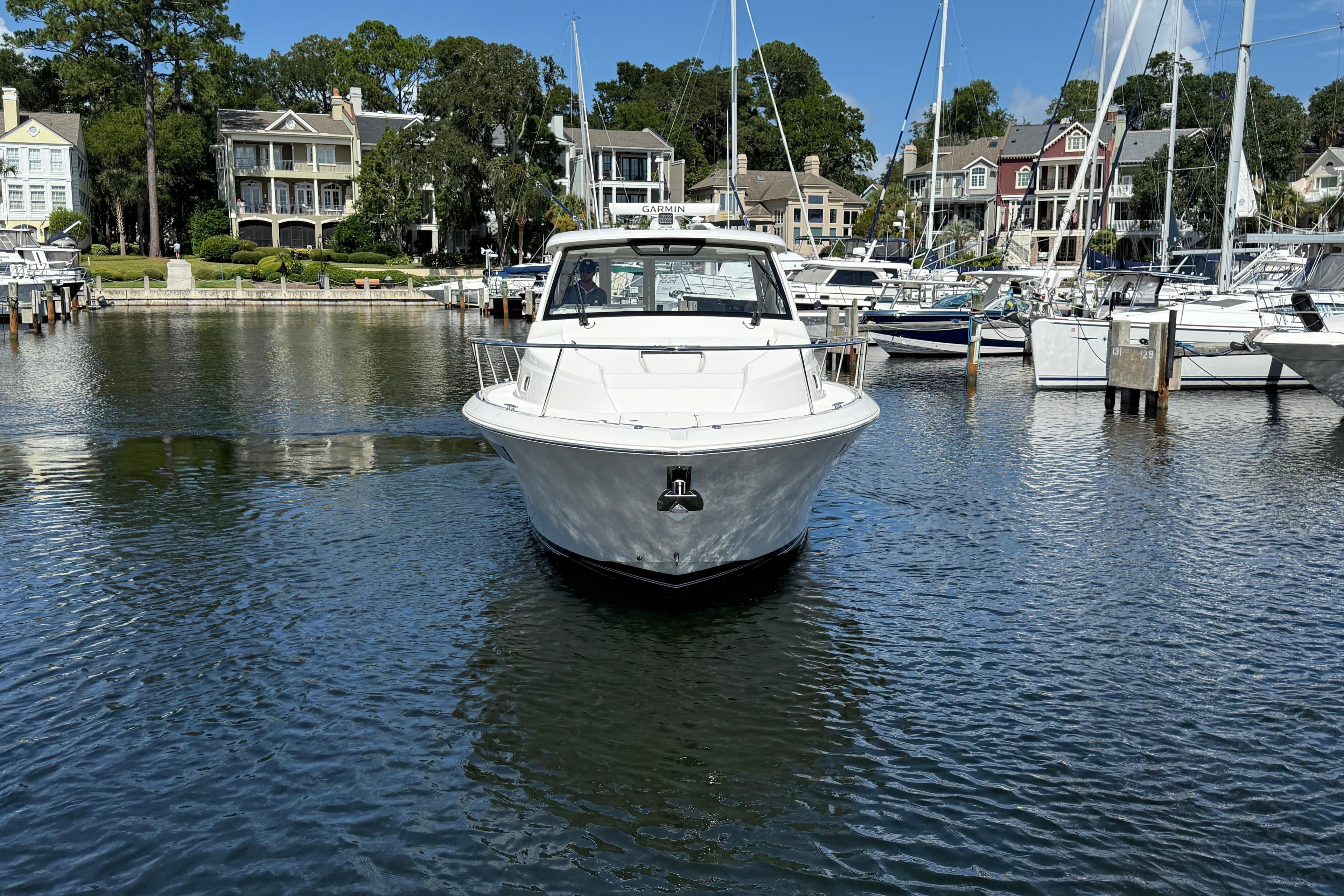 2023 Pursuit OS 355 Offshore boat docked in a scenic marina with waterfront homes.