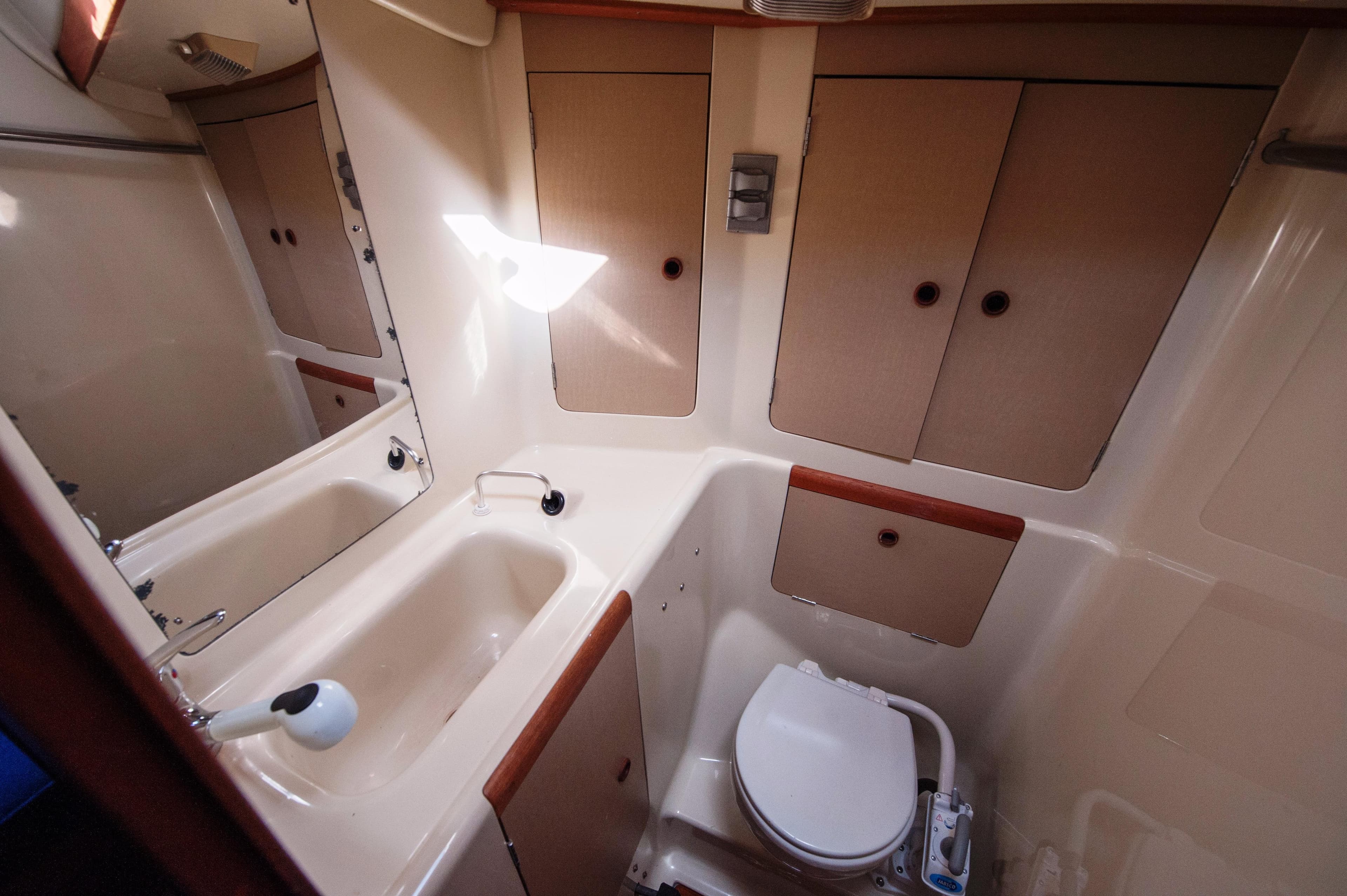 1985 C&C 44 yacht bathroom with sink, toilet, and storage cabinets.