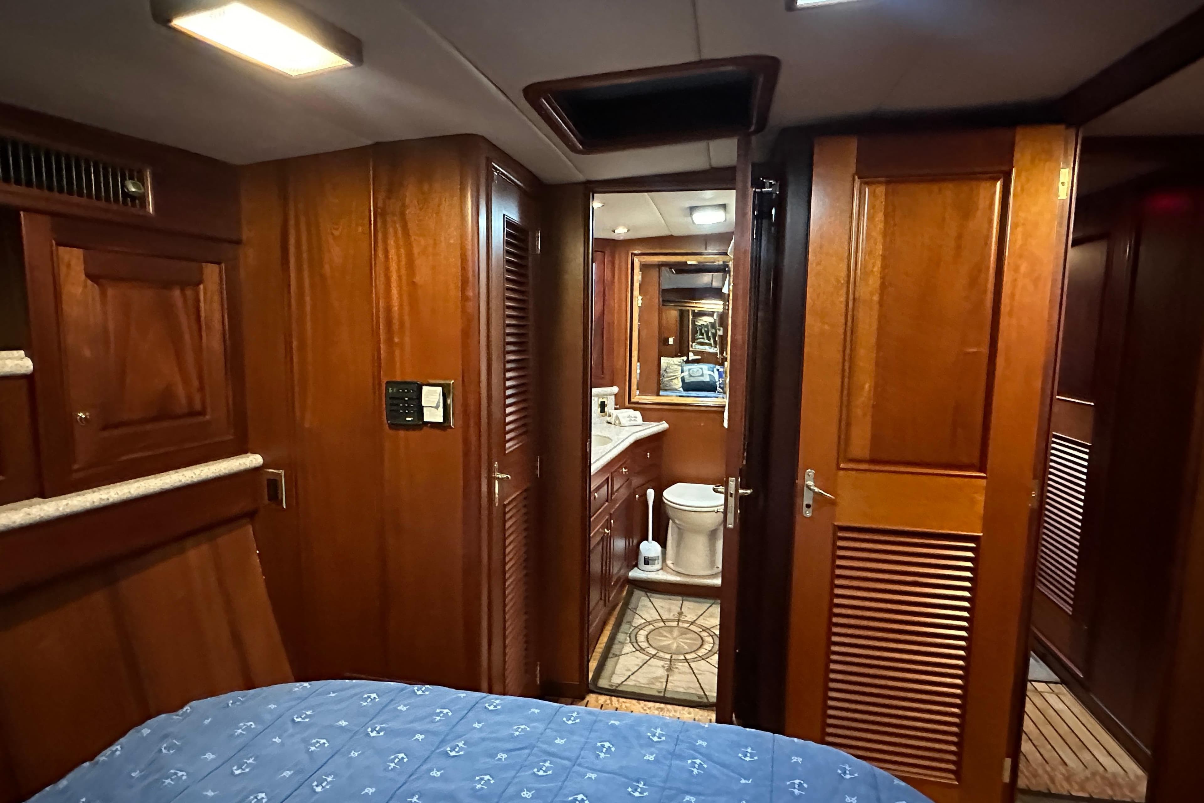 Interior of a 1980 Bertram 58 Convertible yacht, featuring wood paneling and a compact bathroom.