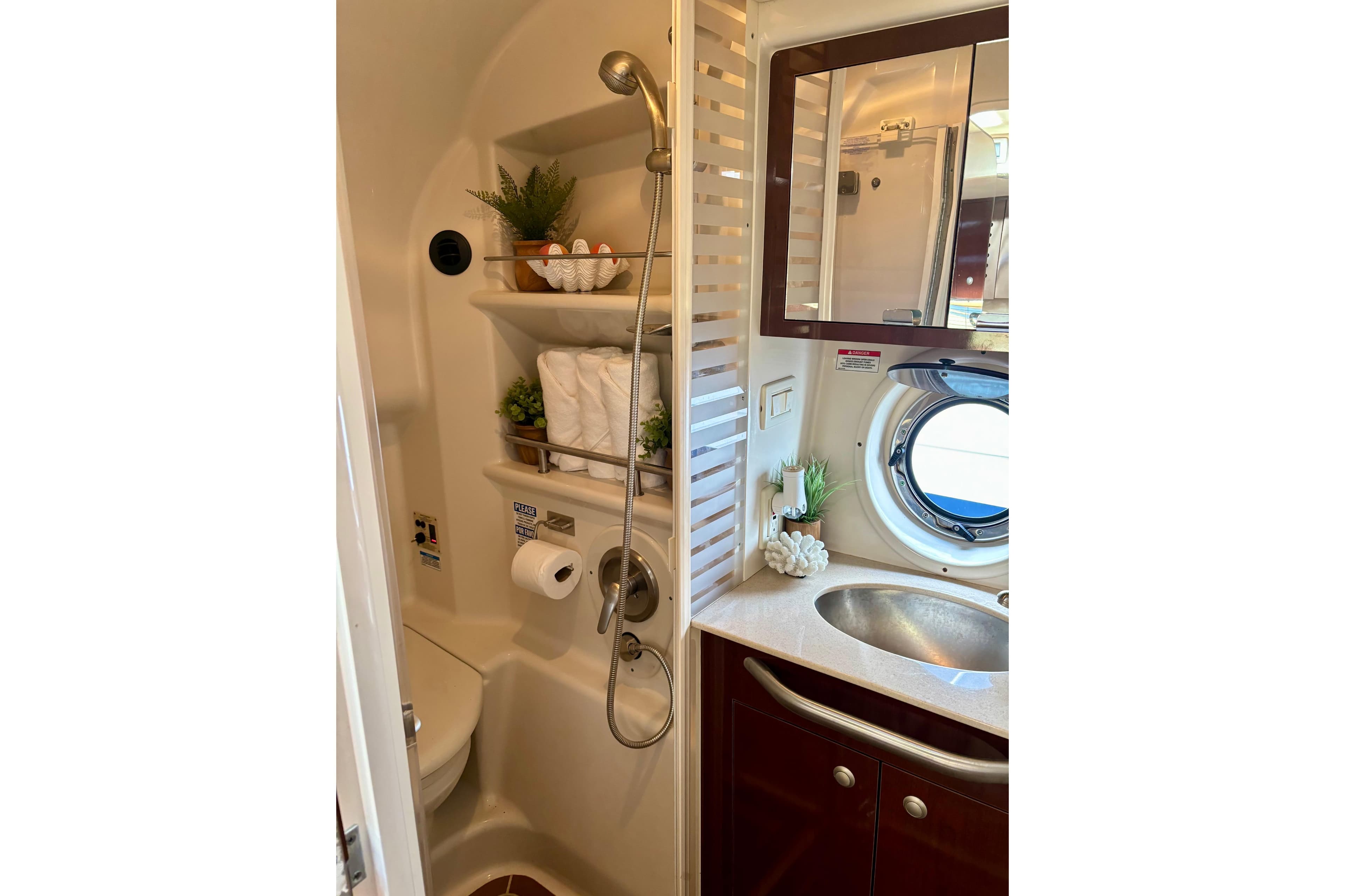 Compact bathroom in 2009 Sea Ray Sundancer 350 yacht with shower, sink, and porthole window.