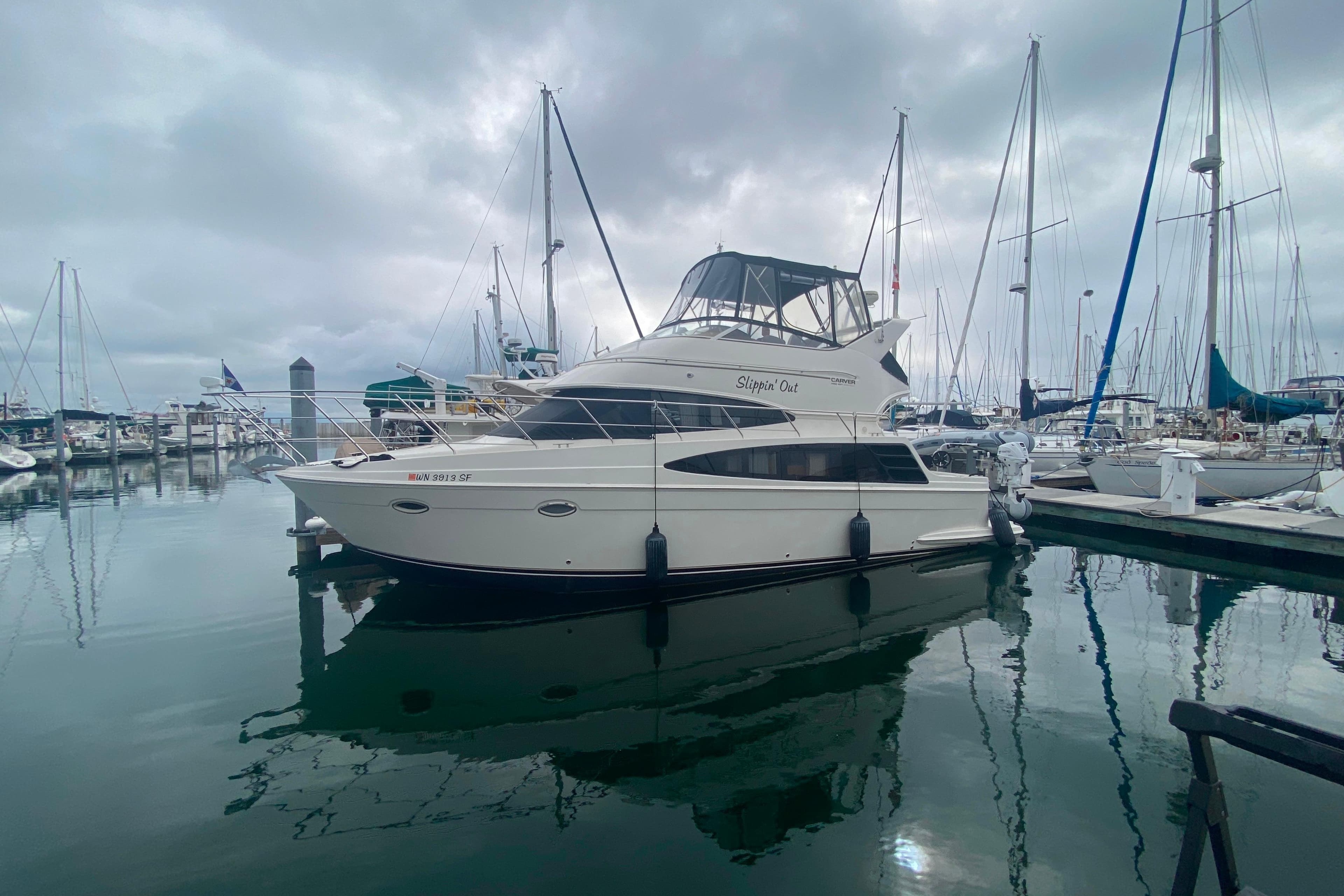 2004 Carver 36 Super Sport yacht docked in a marina under cloudy skies.