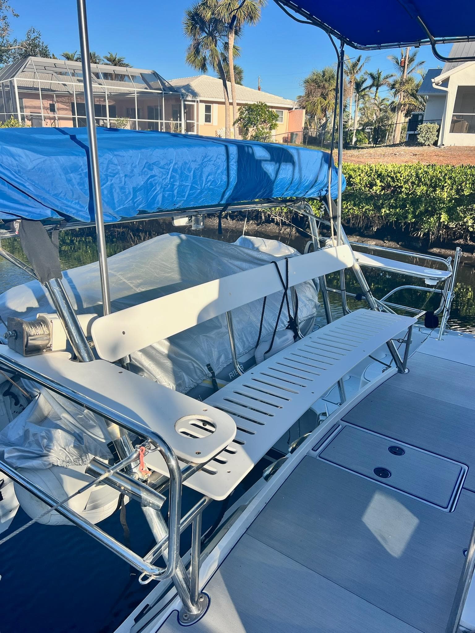 2006 PDQ MV34 boat with blue canopy, docked near waterfront homes.