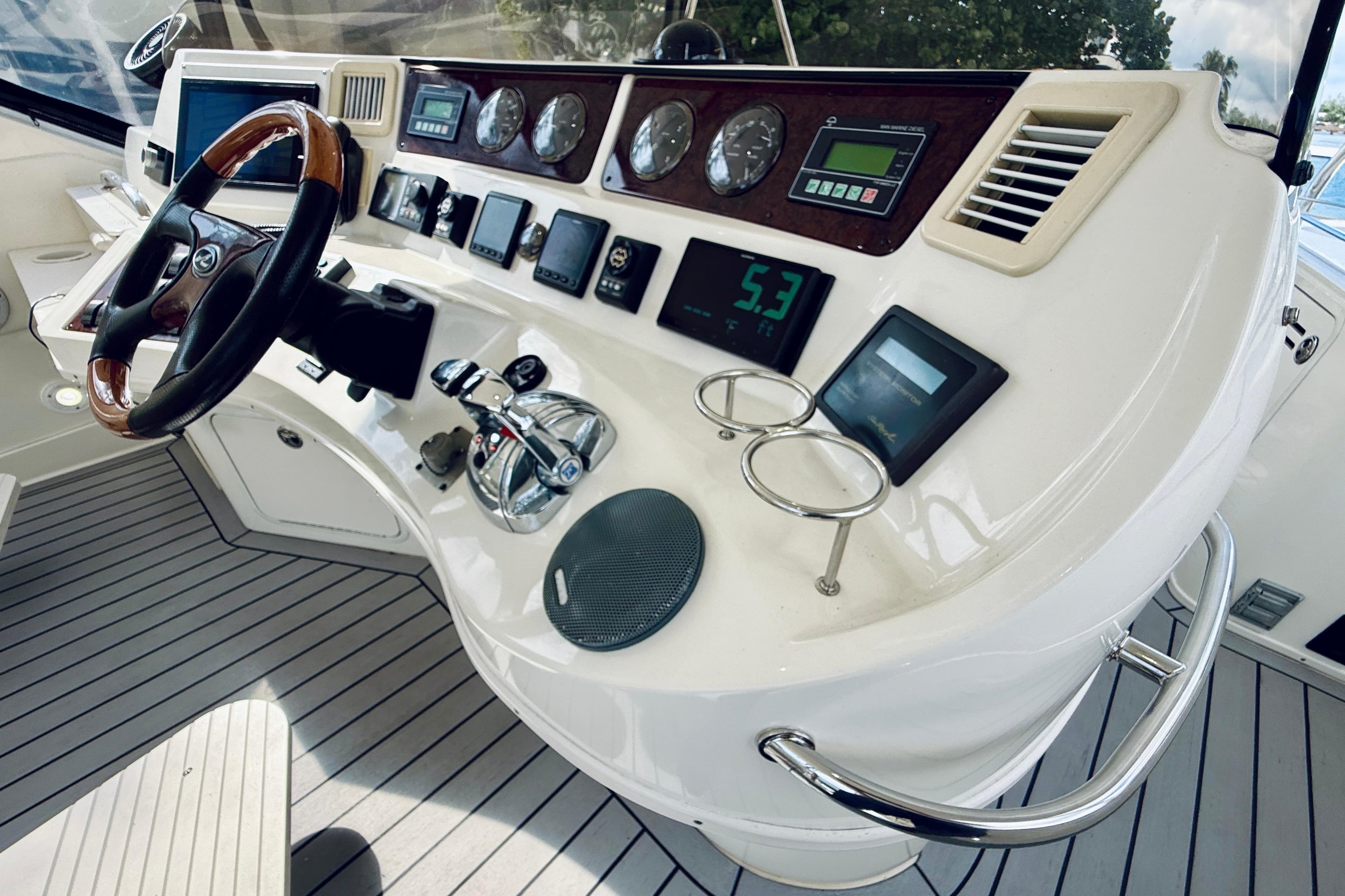 2003 Sea Ray 560 Sedan Bridge helm with gauges, controls, and wooden steering wheel.