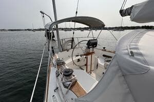 1983 Sabre 38 sailboat cockpit with steering wheel, moored on calm water.