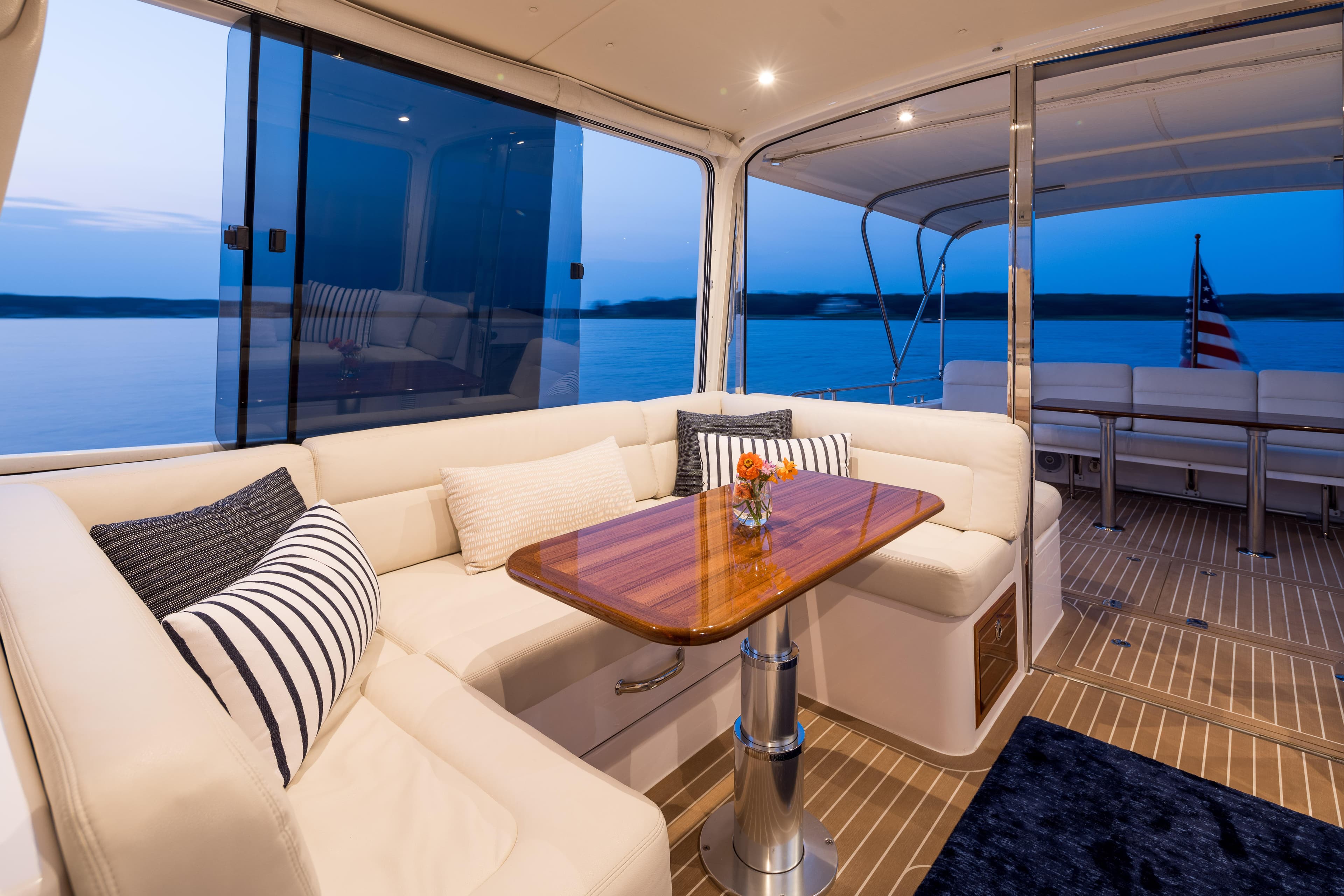 Luxurious 2020 MJM 53z yacht interior with elegant seating and wooden table at sunset.