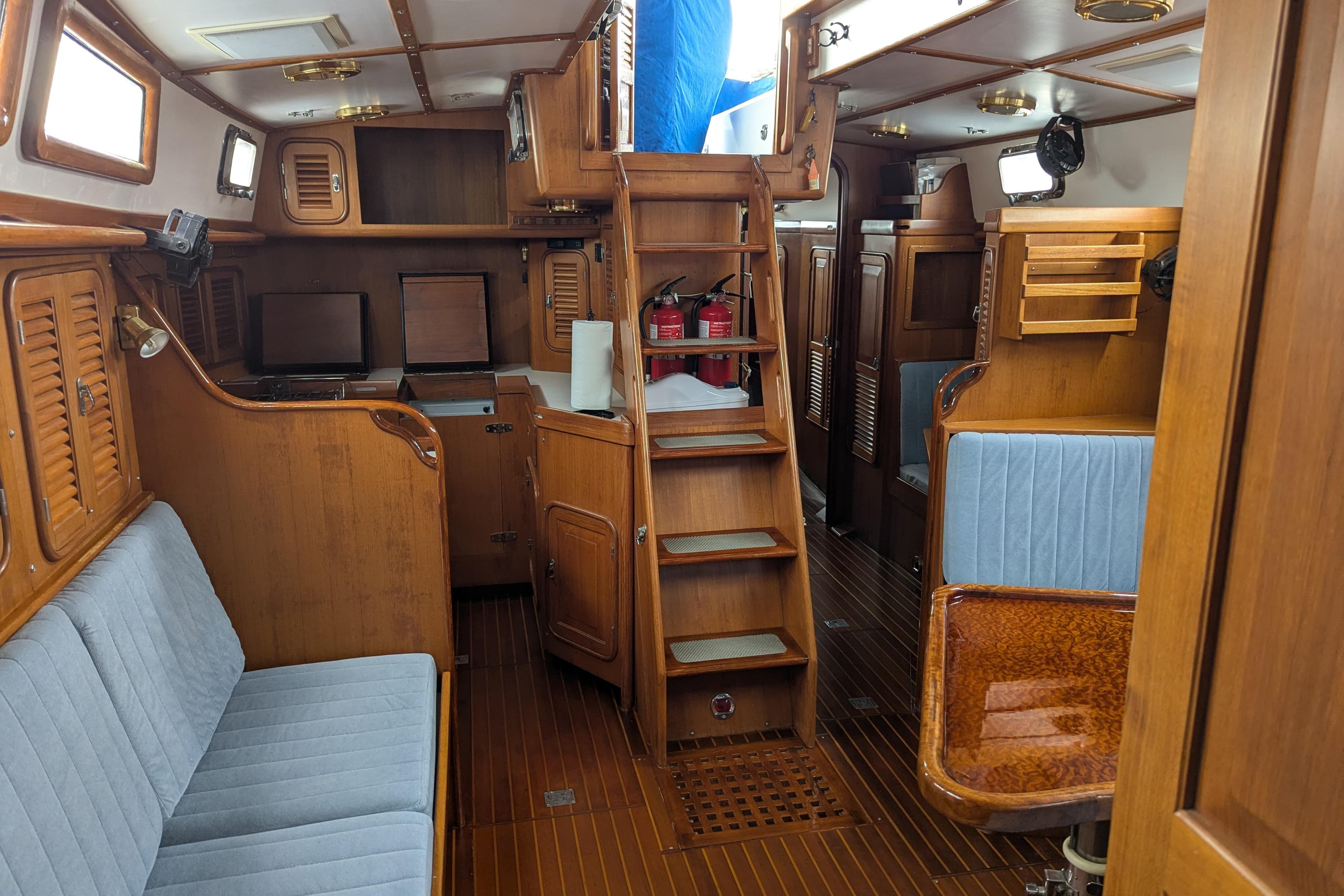 Interior of 1994 Passport Royal Passport 44 yacht with wooden furnishings and blue seating.